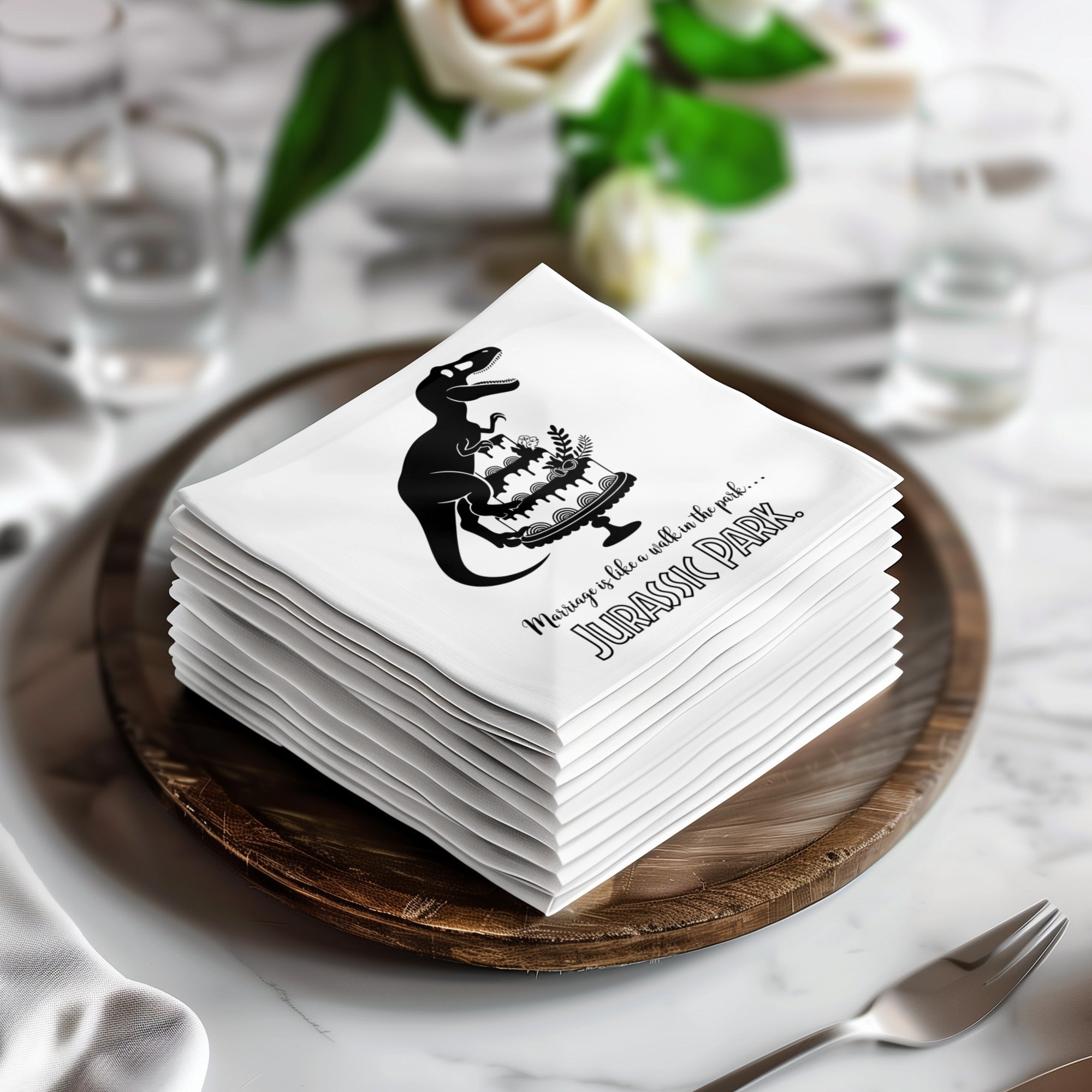 Stack of white napkins with Jurassic Park logo and dinosaur cake graphic.