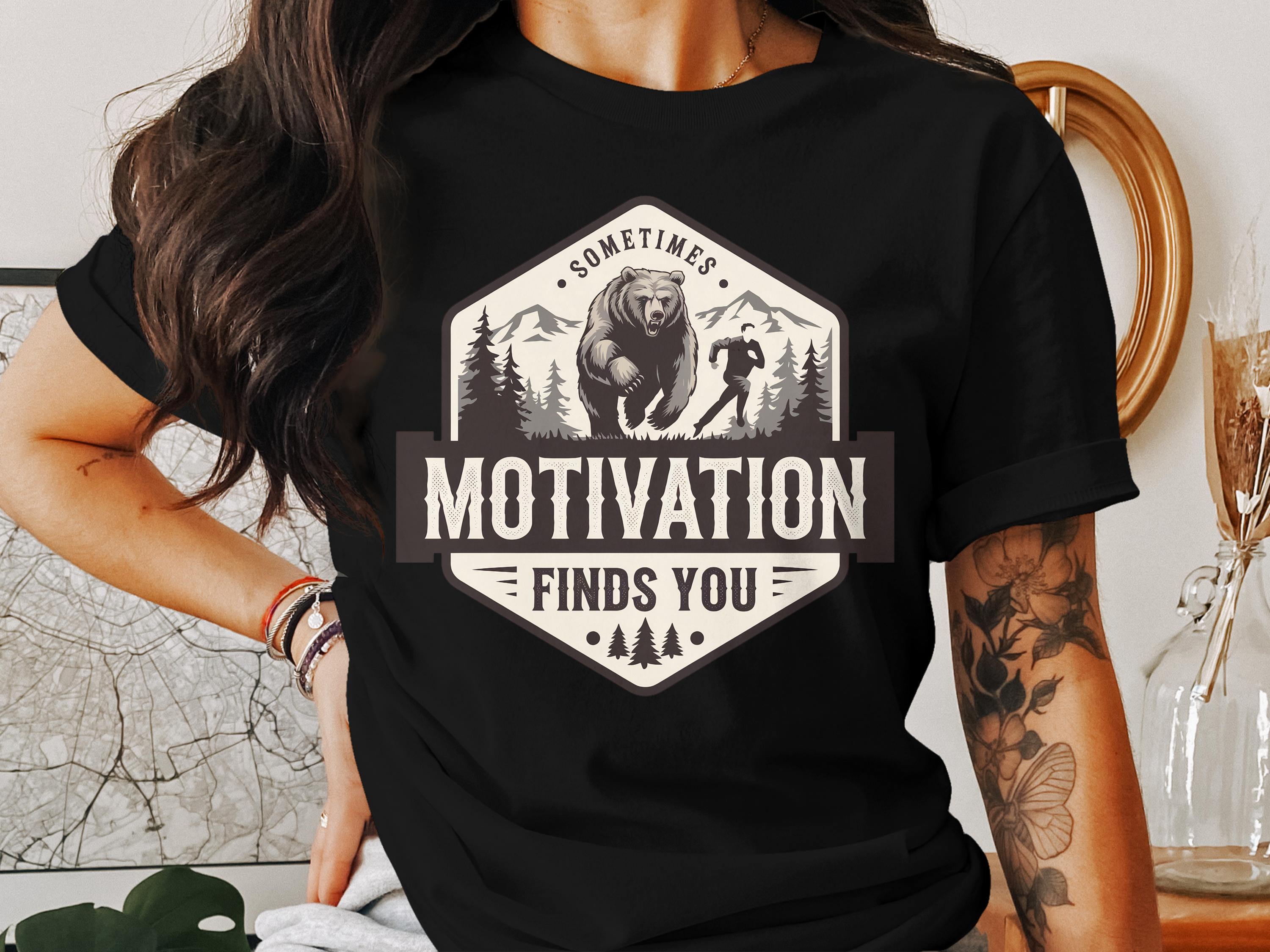 T-shirt graphic: Bear and runner in forest, "Motivation Finds You."