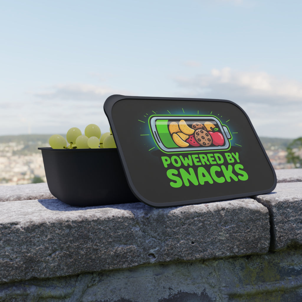 Lunchbox lid displaying a battery icon filled with fruit and cookies, labeled "POWERED BY SNACKS".
