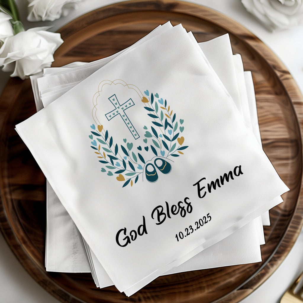 White napkins with "God Bless Emma" and a cross, wreath, and baby shoe design.