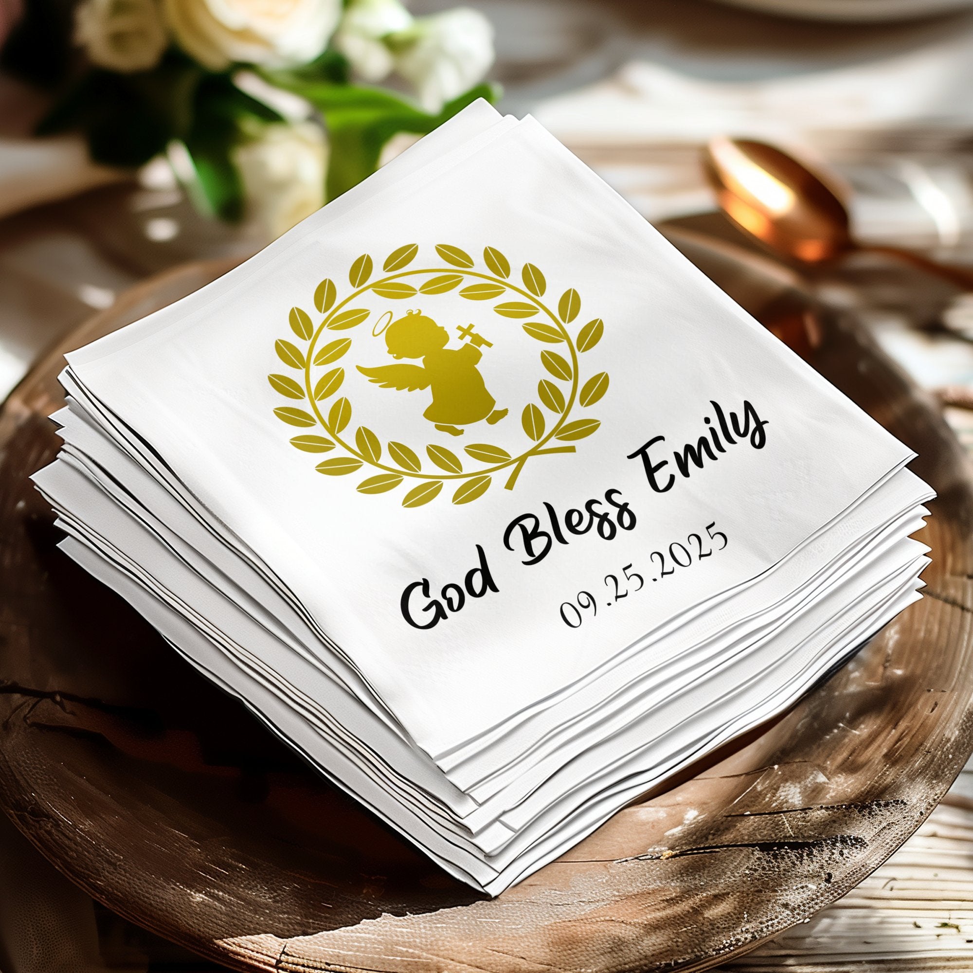 White napkins with gold angel, wreath, and text "God Bless Emily 09.25.2025".