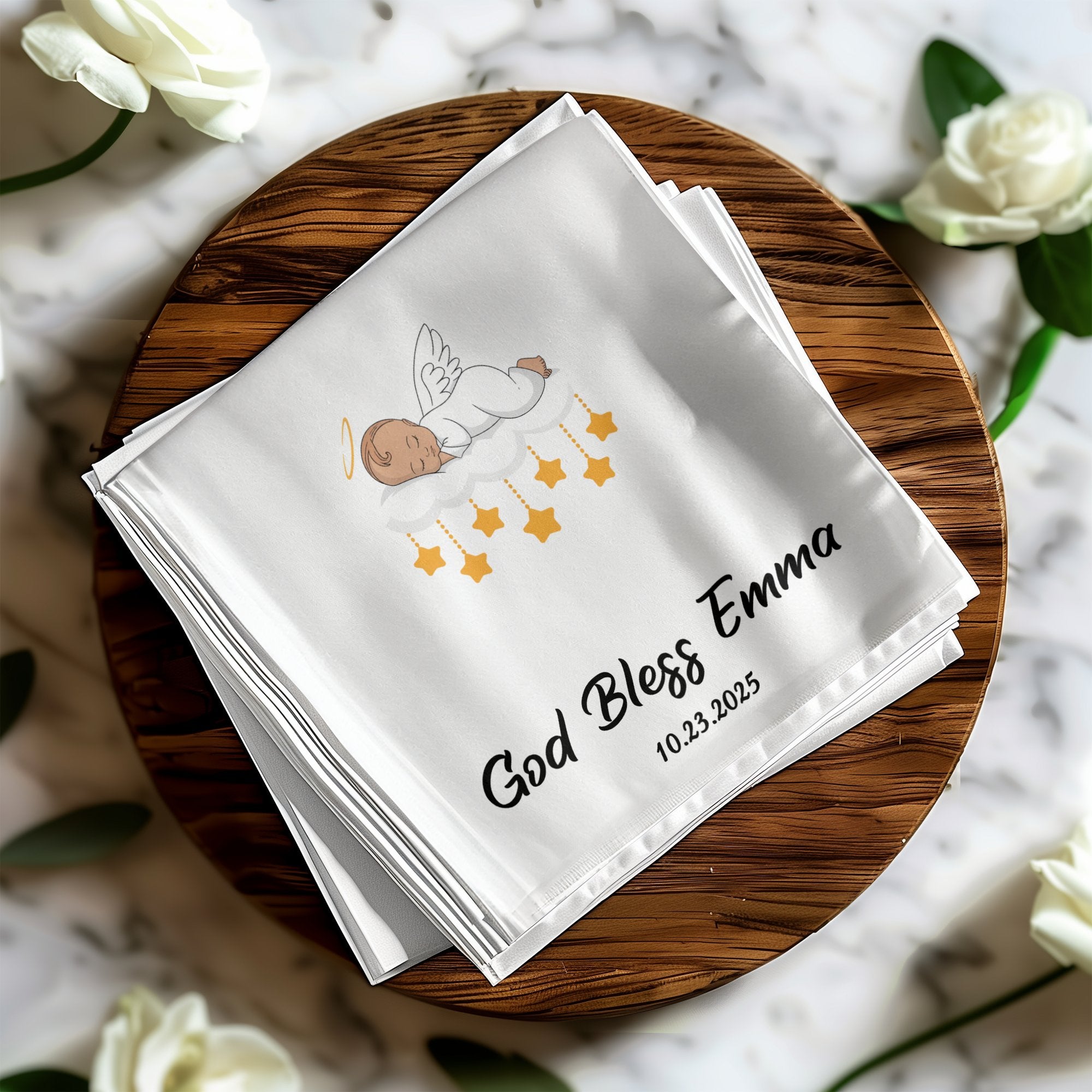 White cloth with "God Bless Emma" and date, featuring an angel on clouds.