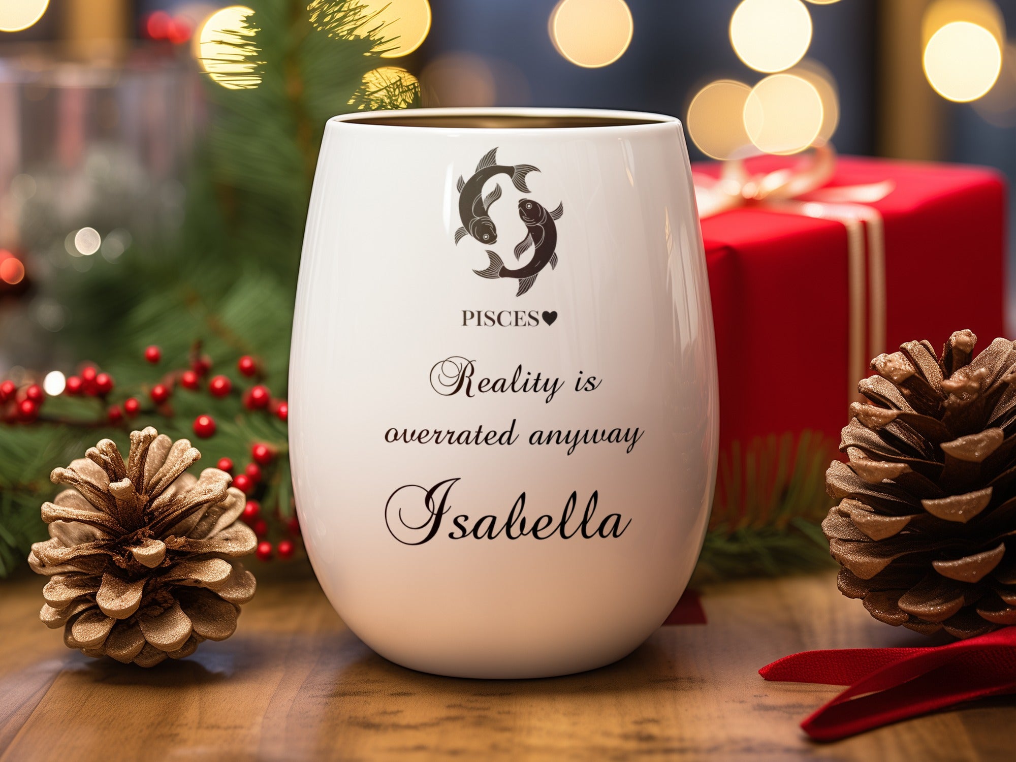 White wine glass with Pisces symbol and text, surrounded by holiday decor.