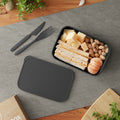 Lunchbox with sandwich, cheese, nuts, and tangerines on a gray mat.