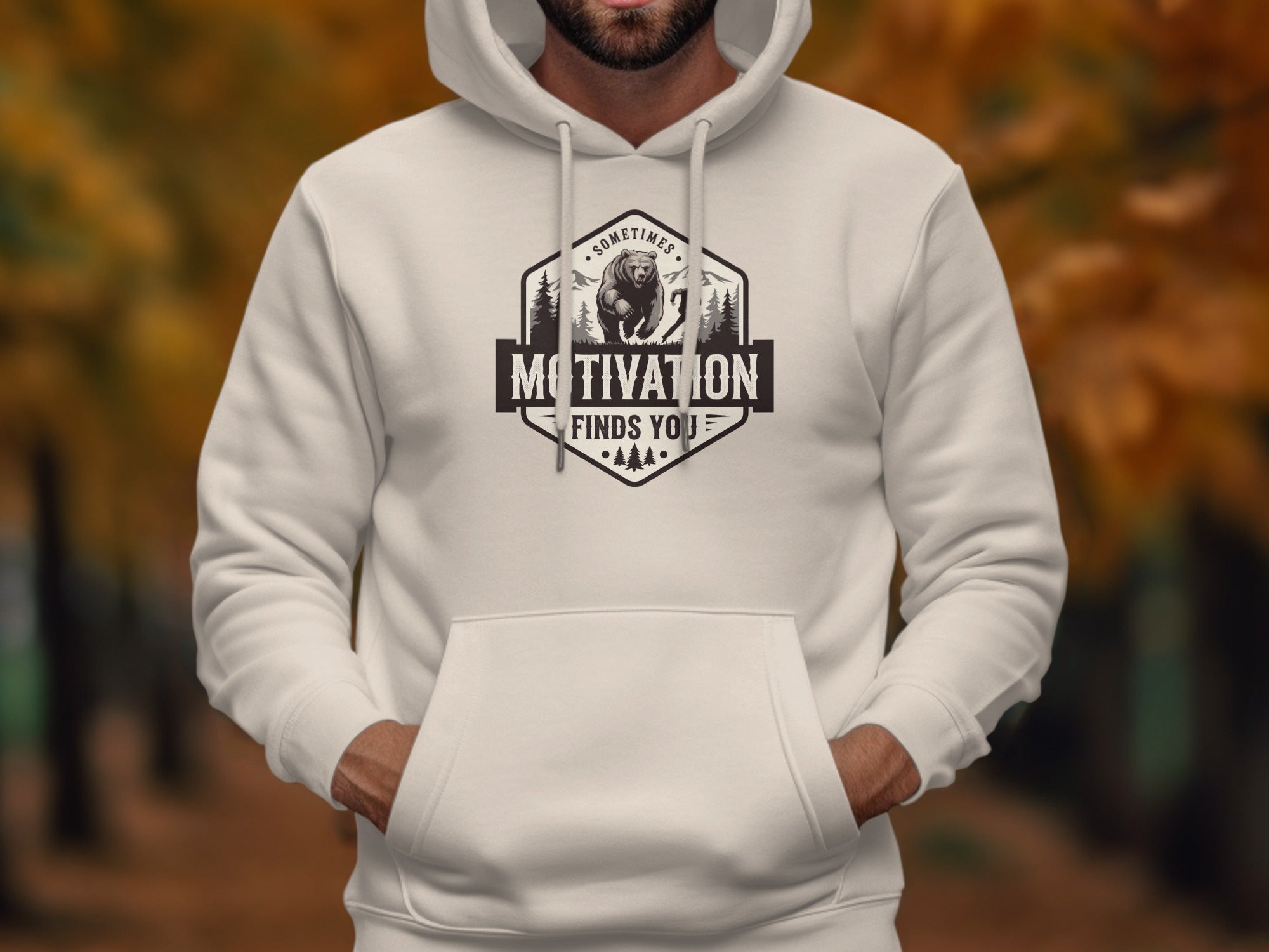 White hoodie with a graphic of a bear in a forest with text "Motivation Finds You".