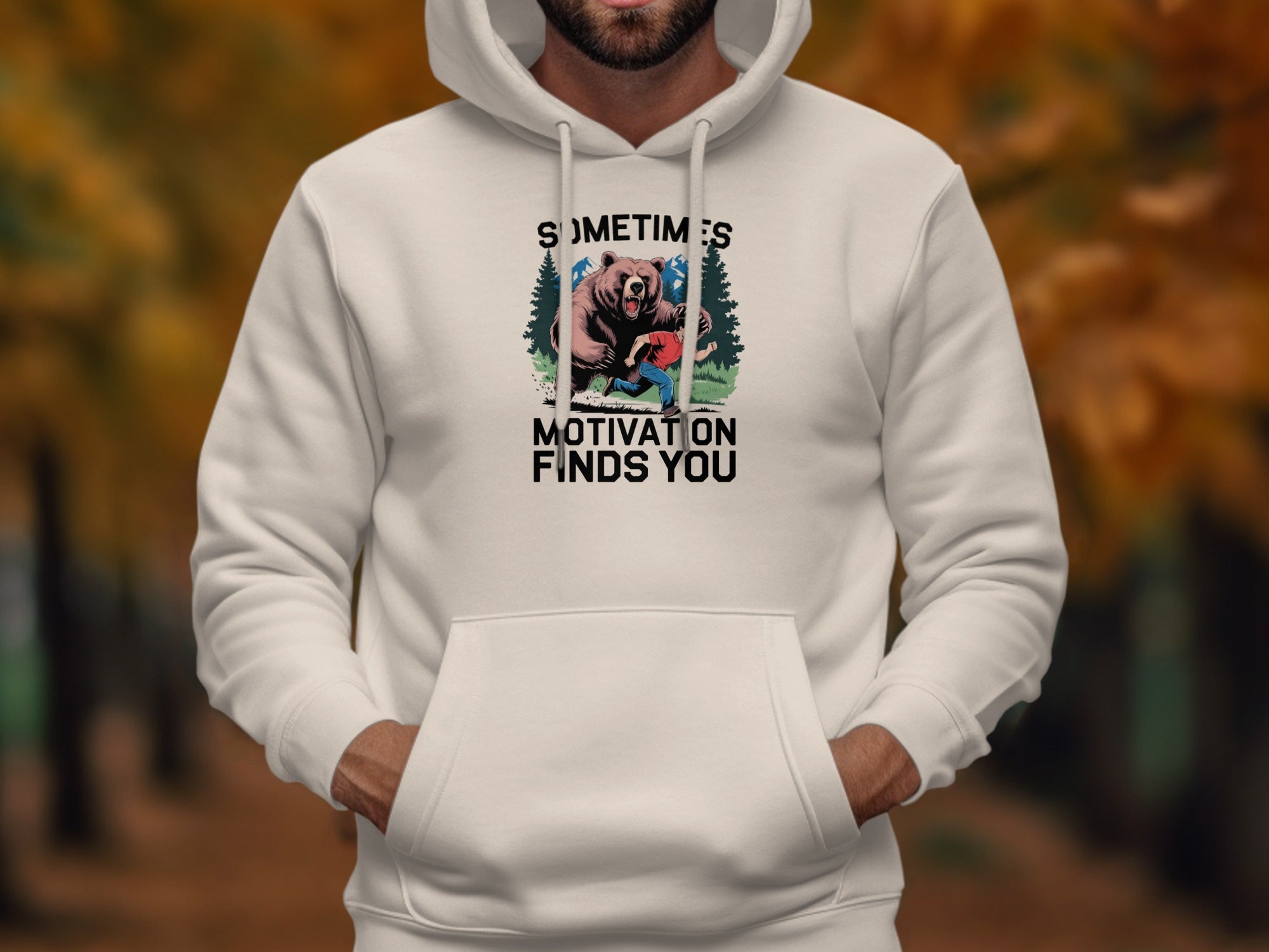 White hoodie with "Sometimes motivation finds you" text and bear-chasing graphic.