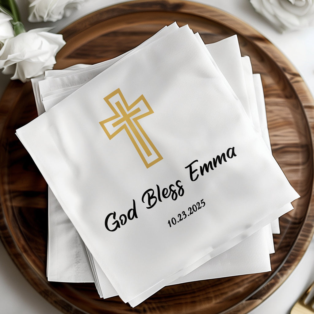 White napkin with gold cross and "God Bless Emma 10.23.2025" text.