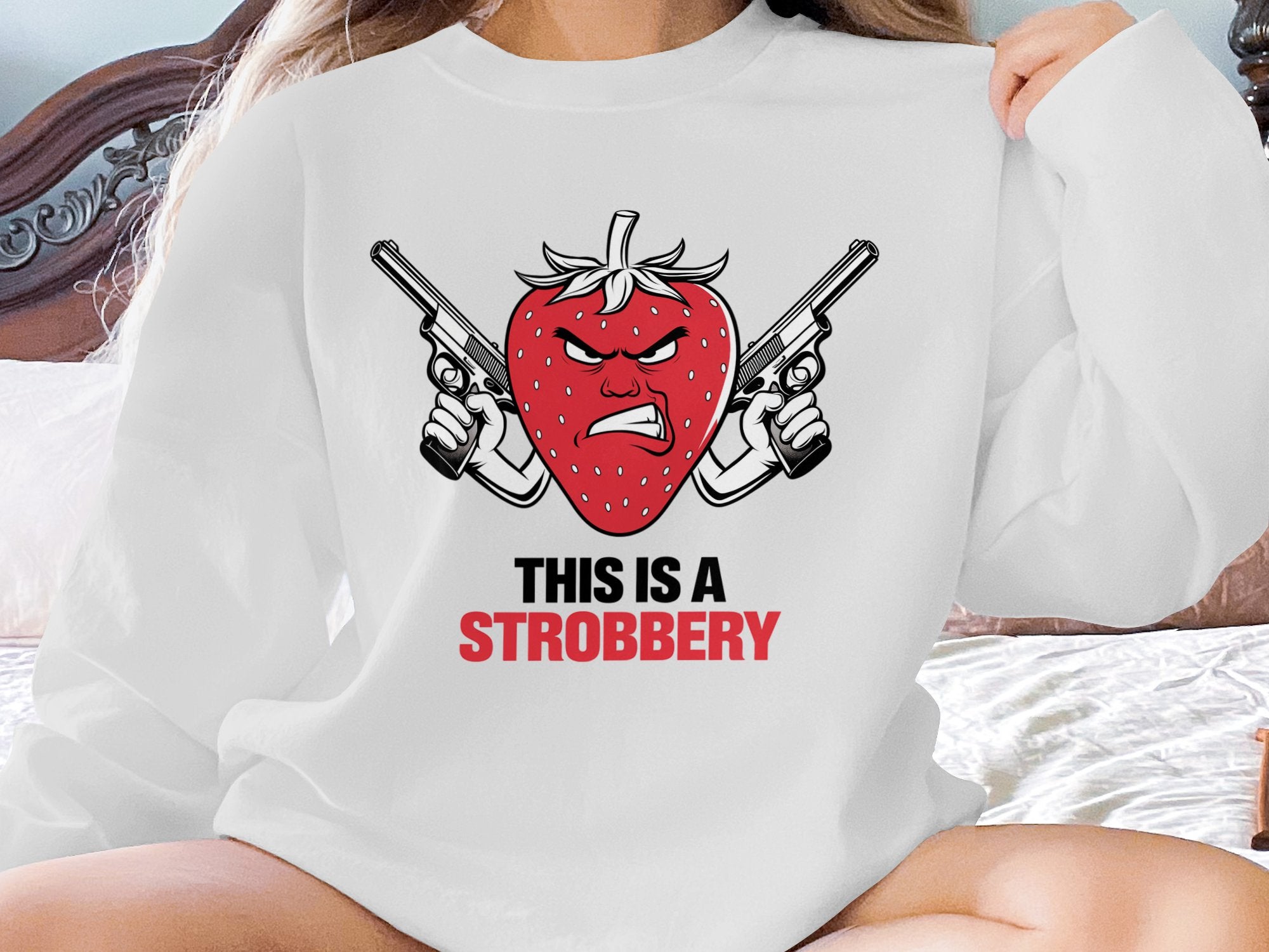 White sweatshirt with angry strawberry holding two guns and text "This is a Strobbery".
