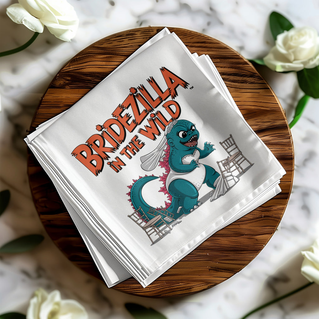 White napkin with "BRIDEZILLA IN THE WILD" text and cartoon dinosaur bride.