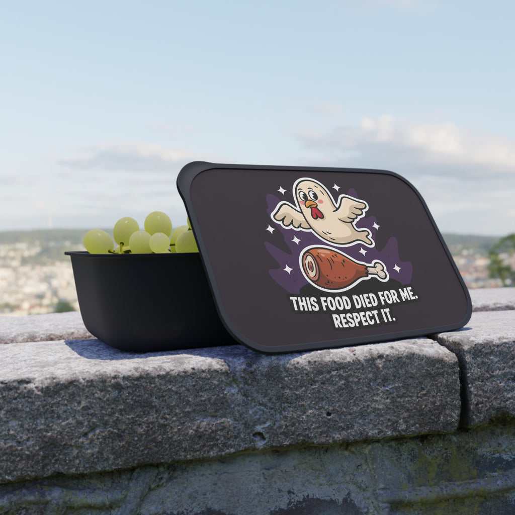 Black lunchbox with lid showing cartoon chicken and grapes, text "This food died for me. Respect it."