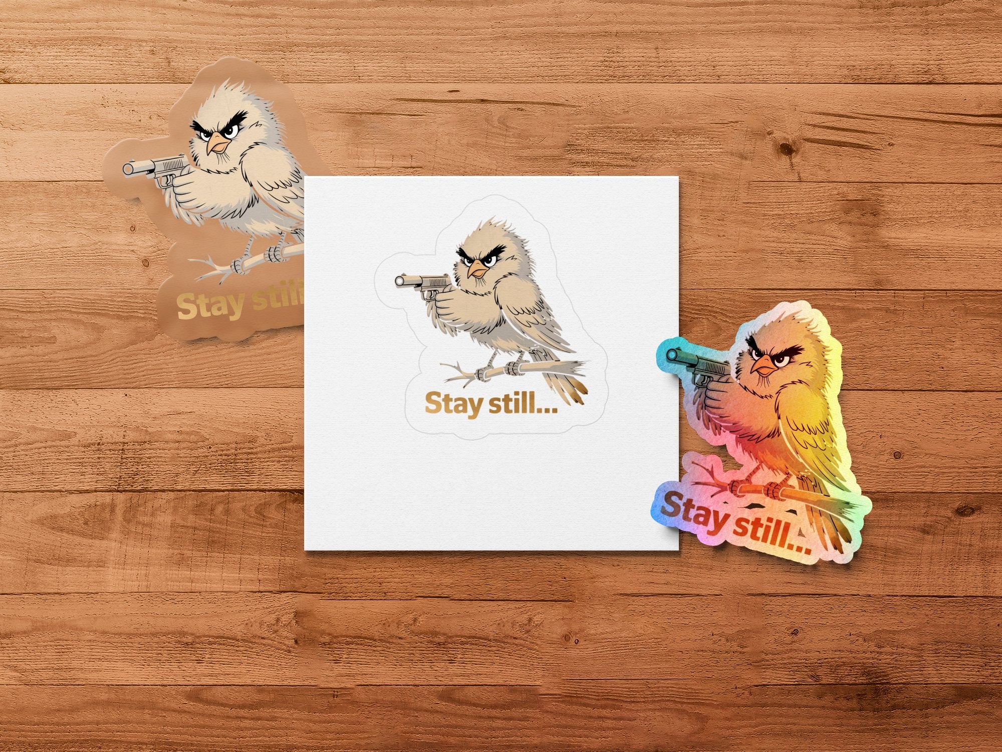 Angry bird with gun sticker and "Stay still..." text on wooden background.