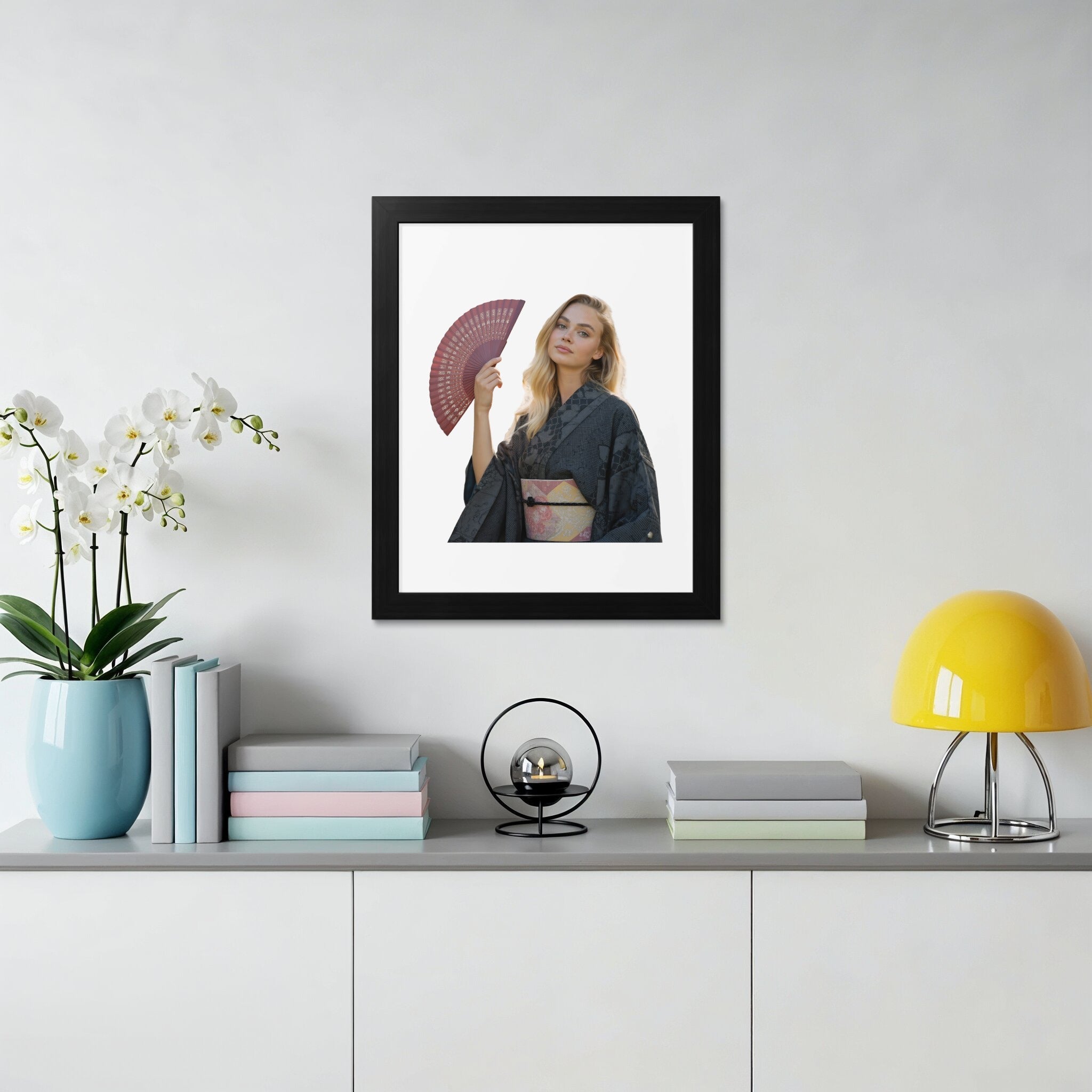 Woman in dark kimono holding red fan, framed on wall.