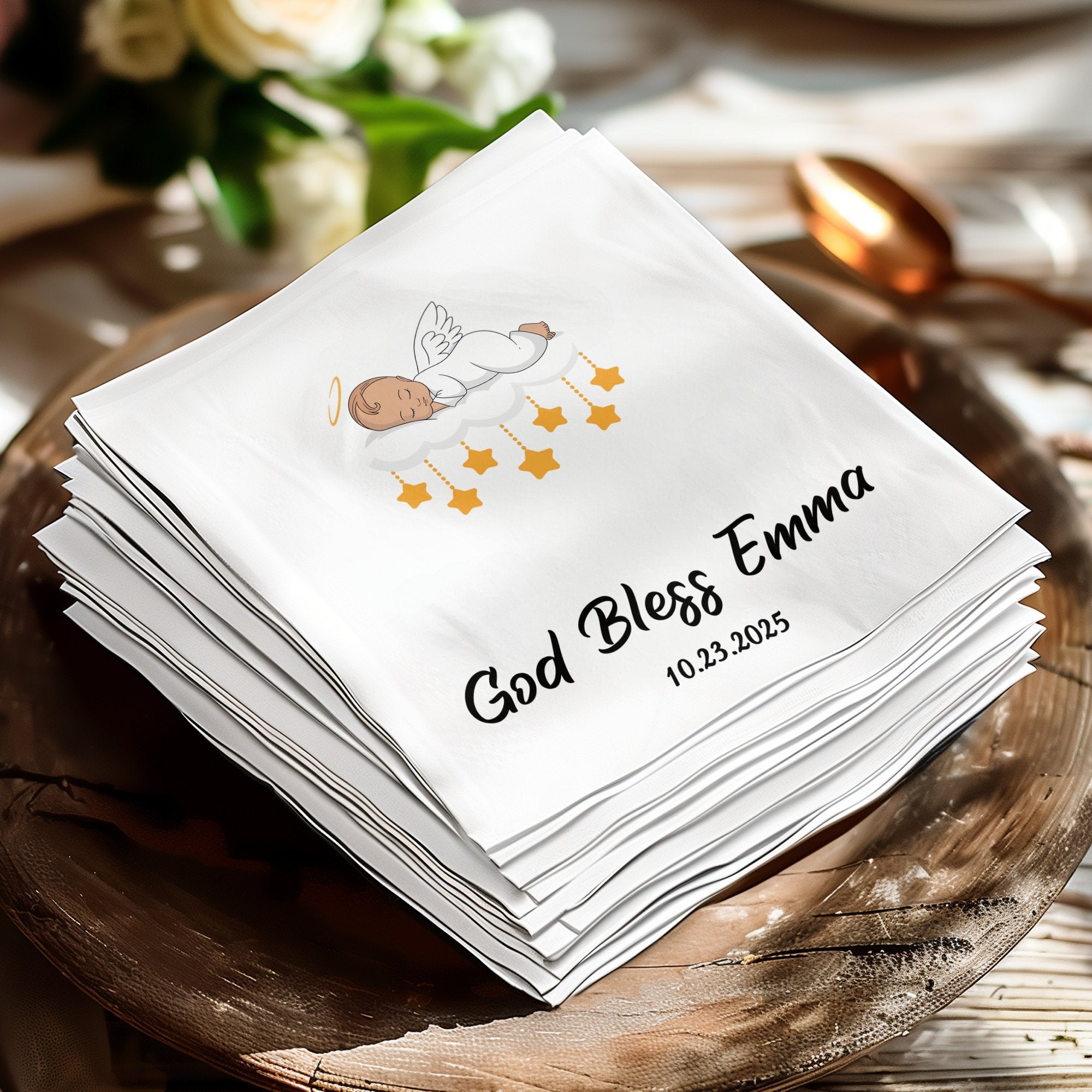 White napkin with "God Bless Emma" and date 10.23.2025, featuring an angel and stars.