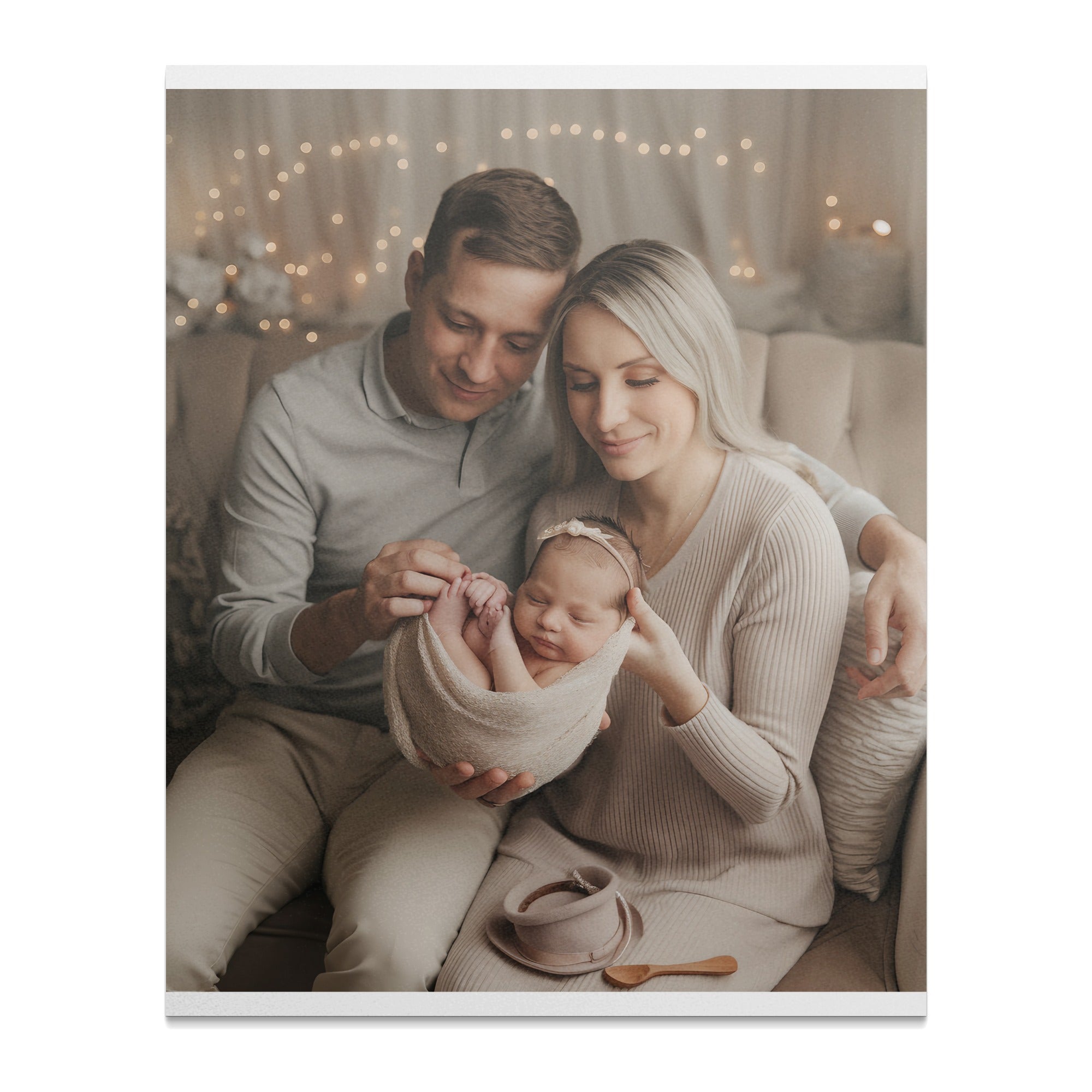 Parents holding their newborn baby girl wrapped in a tan blanket.