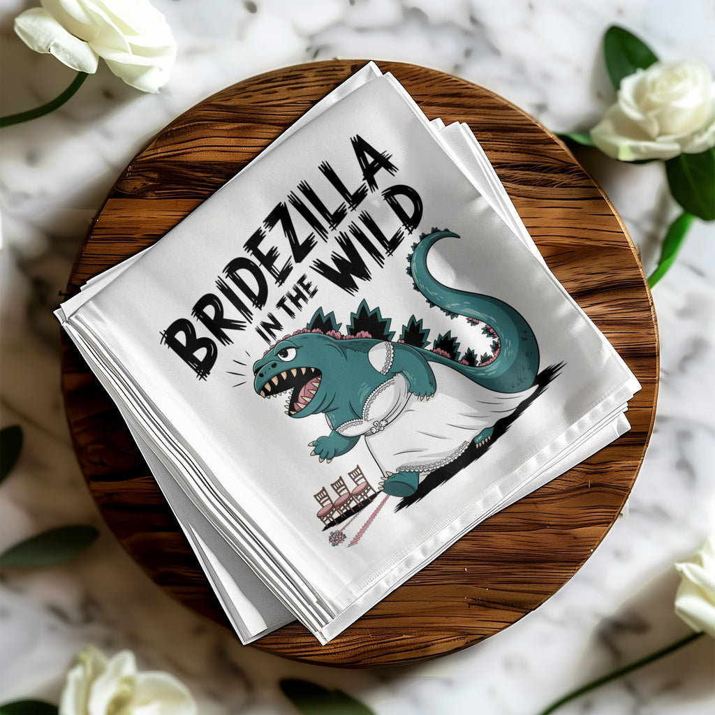 White napkin with "BRIDEZILLA IN THE WILD" text and illustration of a Godzilla-like creature in a wedding dress.