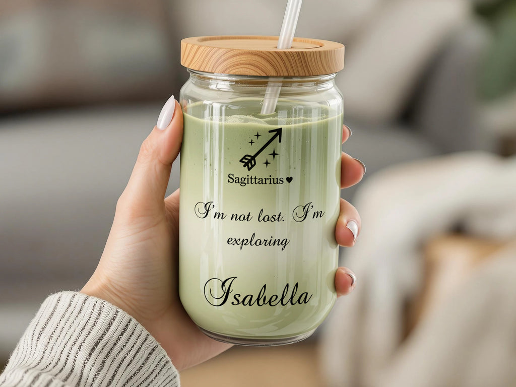 Glass tumbler with wooden lid, straw, and "Sagittarius, I'm not lost. Isabella" text.