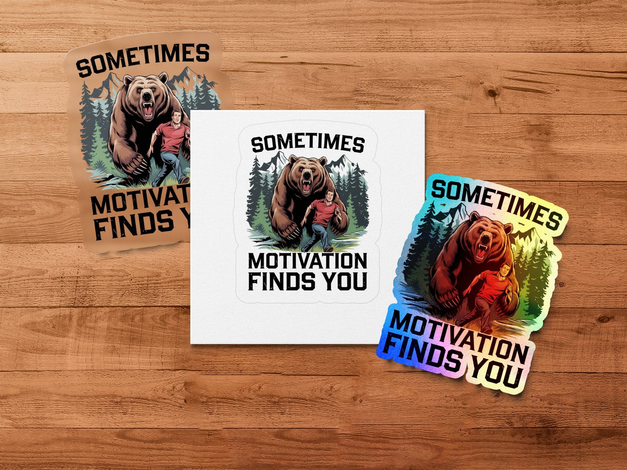 Two stickers and a square decal with a bear and man, saying "Sometimes Motivation Finds You."