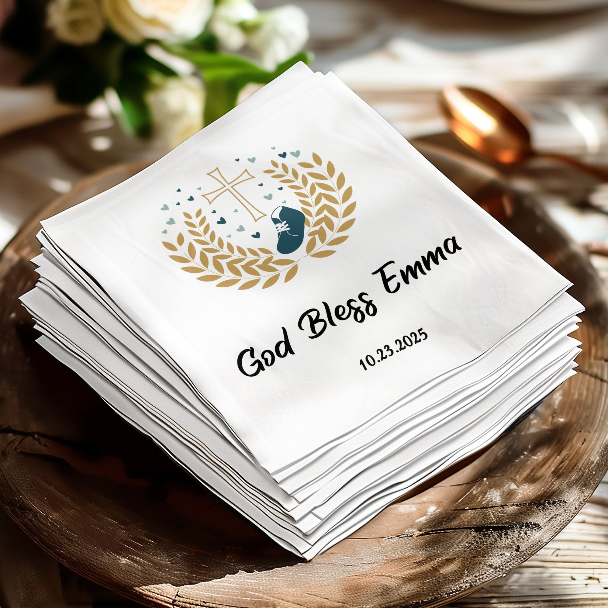 White napkin with "God Bless Emma" and "10.23.2025" in gold.