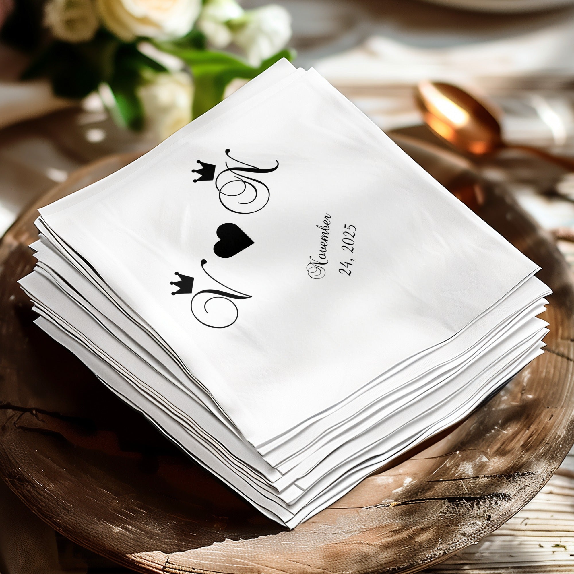 Stack of white napkins with black monogram of "N" and "M" with a heart and crowns.
