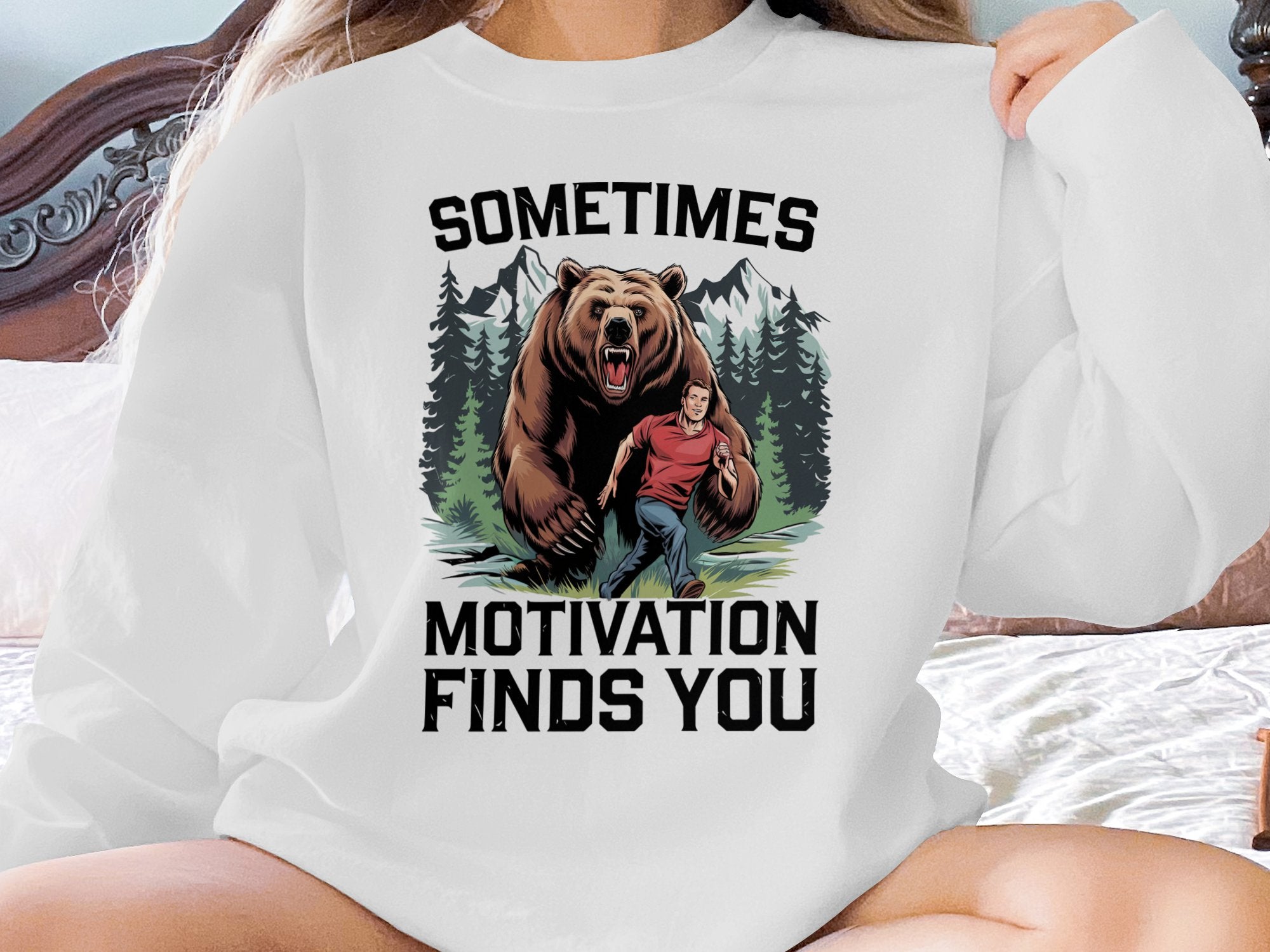 Bear chasing a man with text "Sometimes Motivation Finds You" on sweatshirt.
