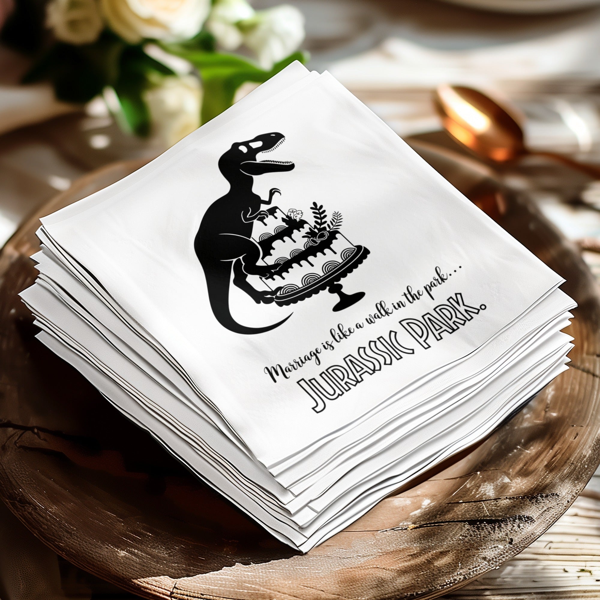 Napkin with dinosaur carrying cake and "Marriage is like a walk in the park... Jurassic Park" text.