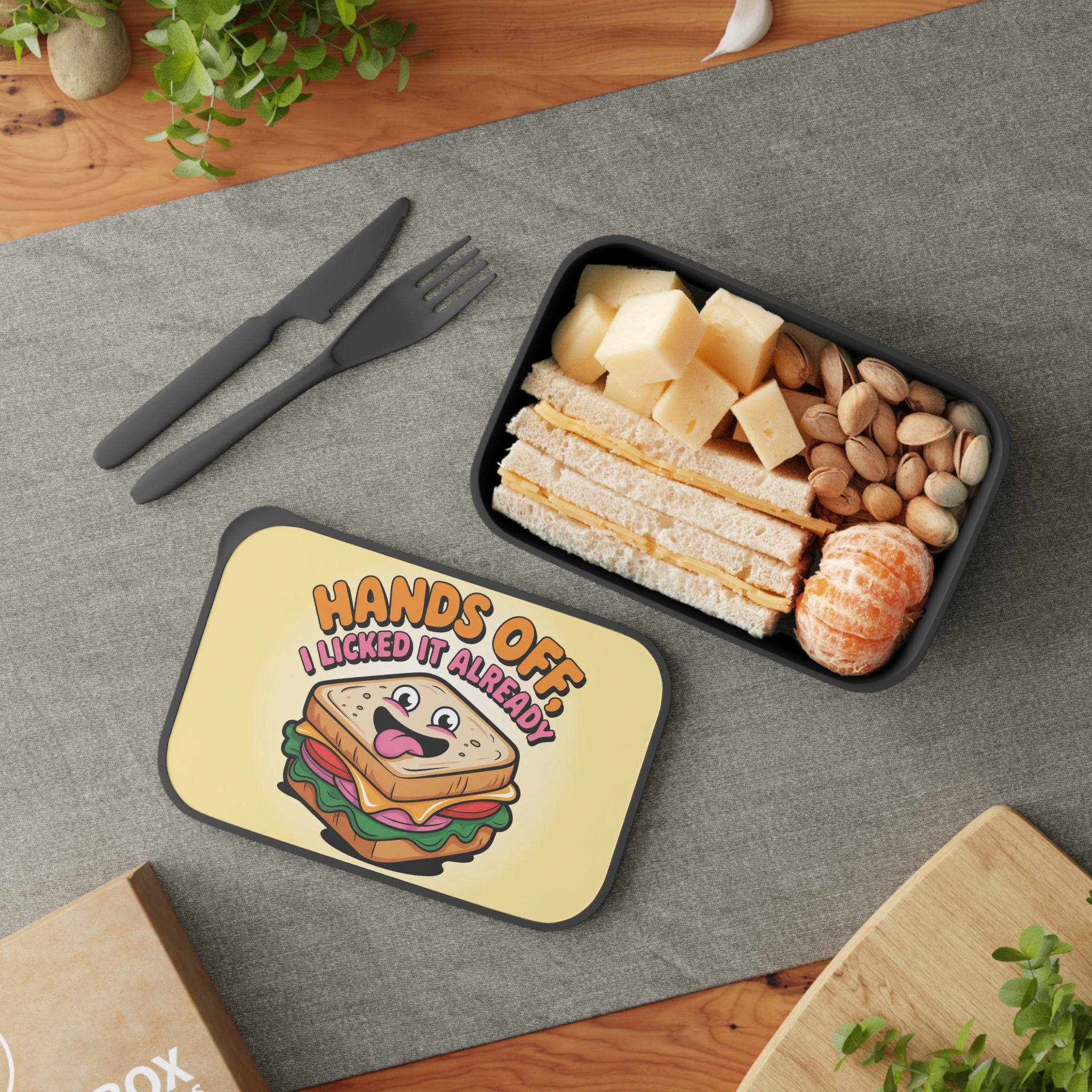 Lunchbox with sandwich, cheese, nuts, and fruit, featuring "Hands off I licked it already" text.