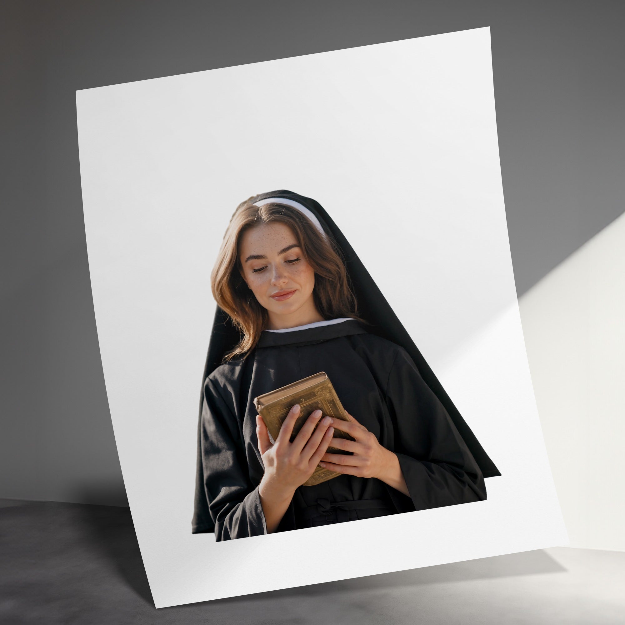 Nun in habit holding a book, looking down.