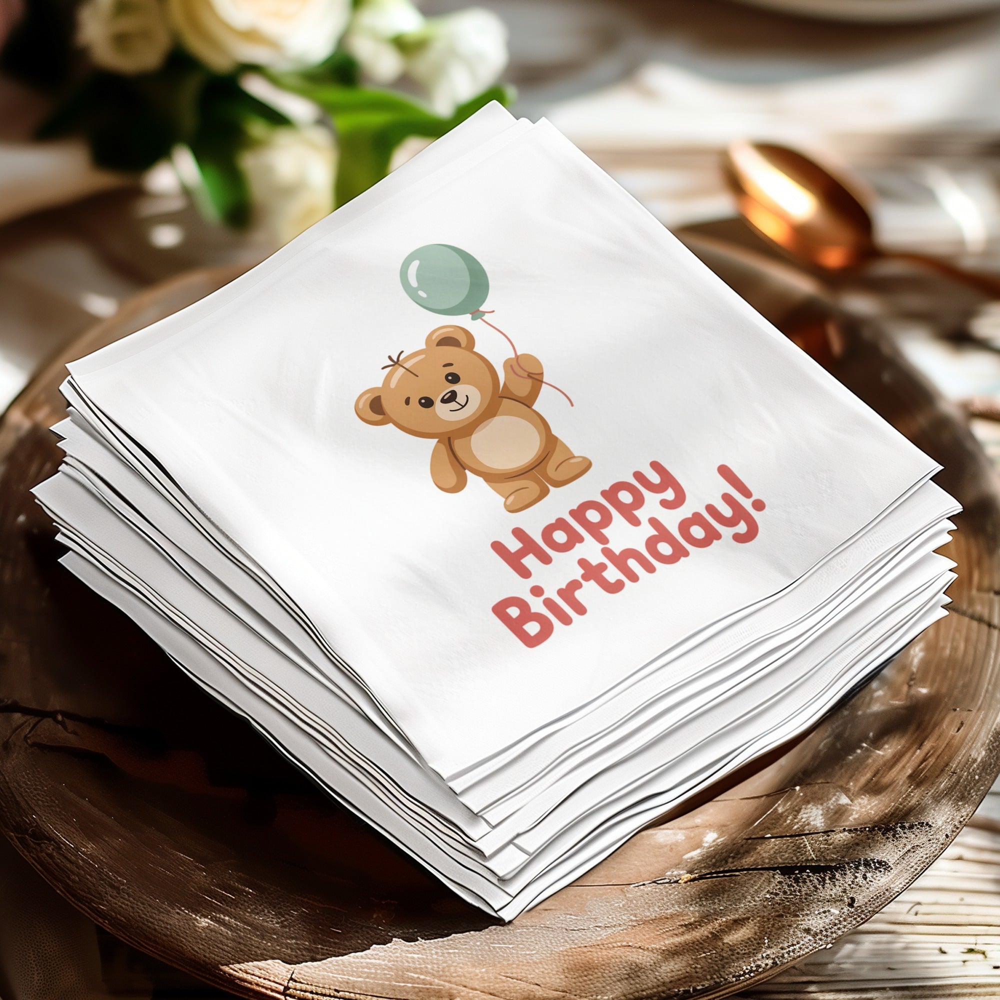 Stack of white napkins with a teddy bear holding a balloon and "Happy Birthday!"