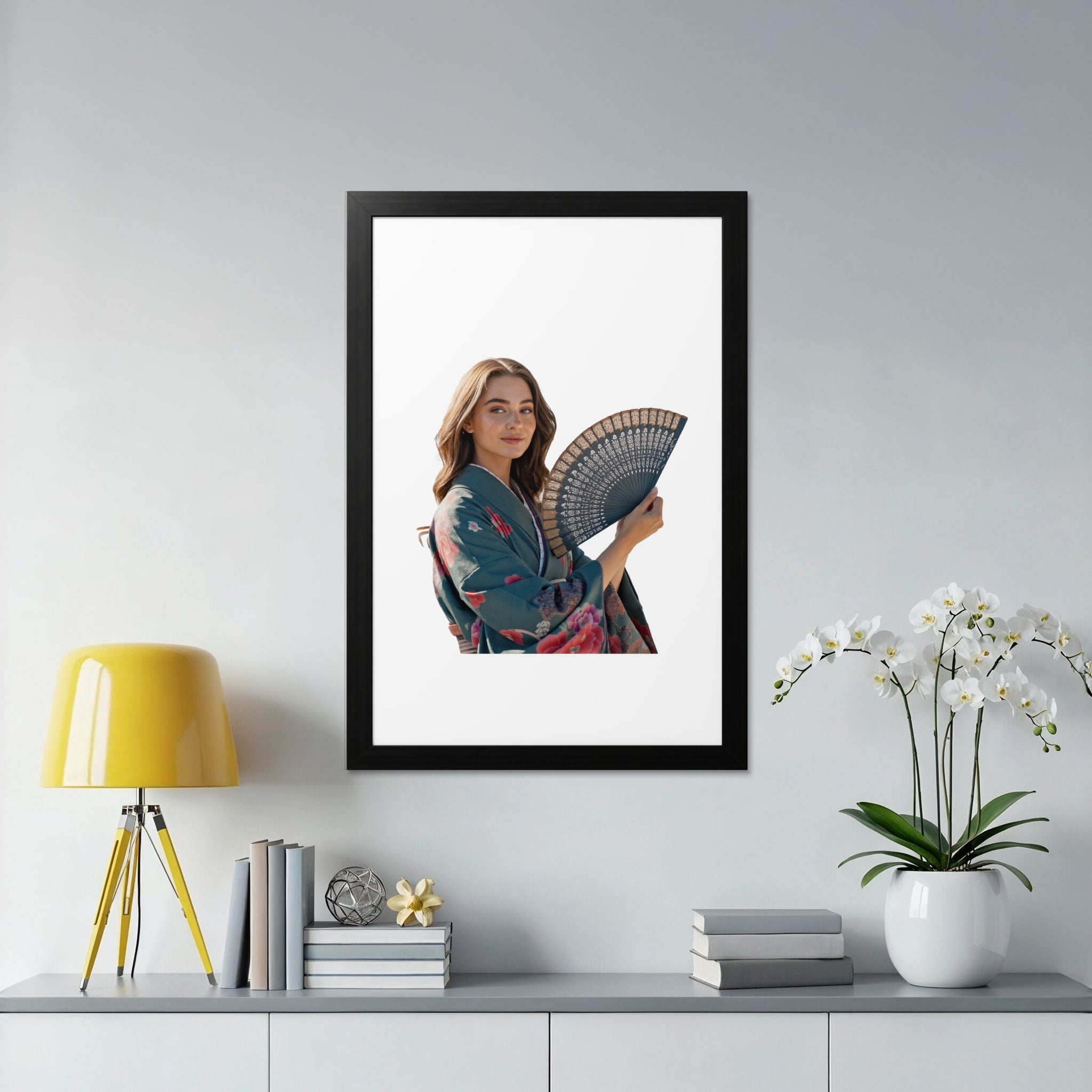 Woman in teal kimono holding black fan, standing by white orchid.