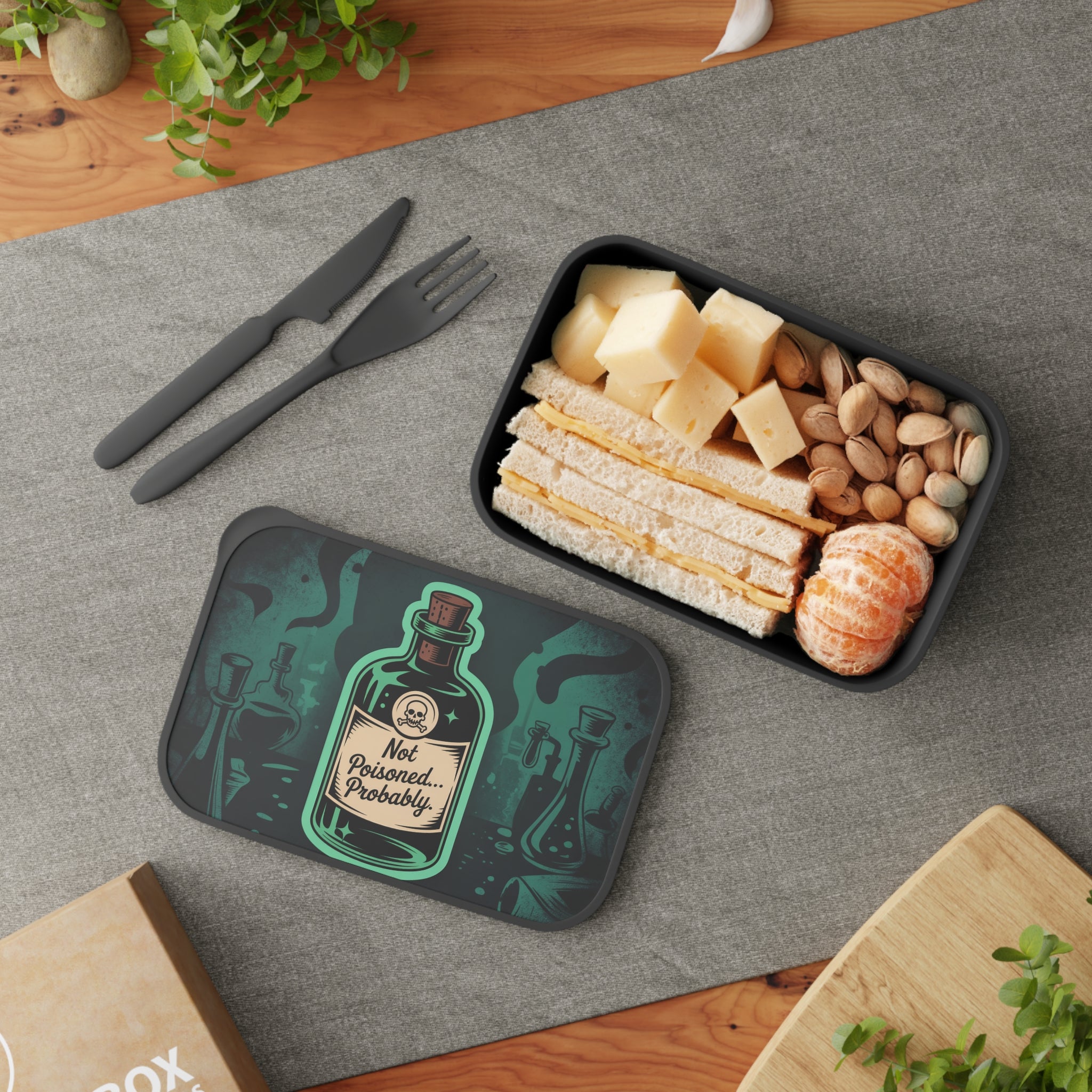 Lunchbox with "Not Poisoned... Probably" text, containing sandwich, cheese, pistachios, and mandarin oranges.