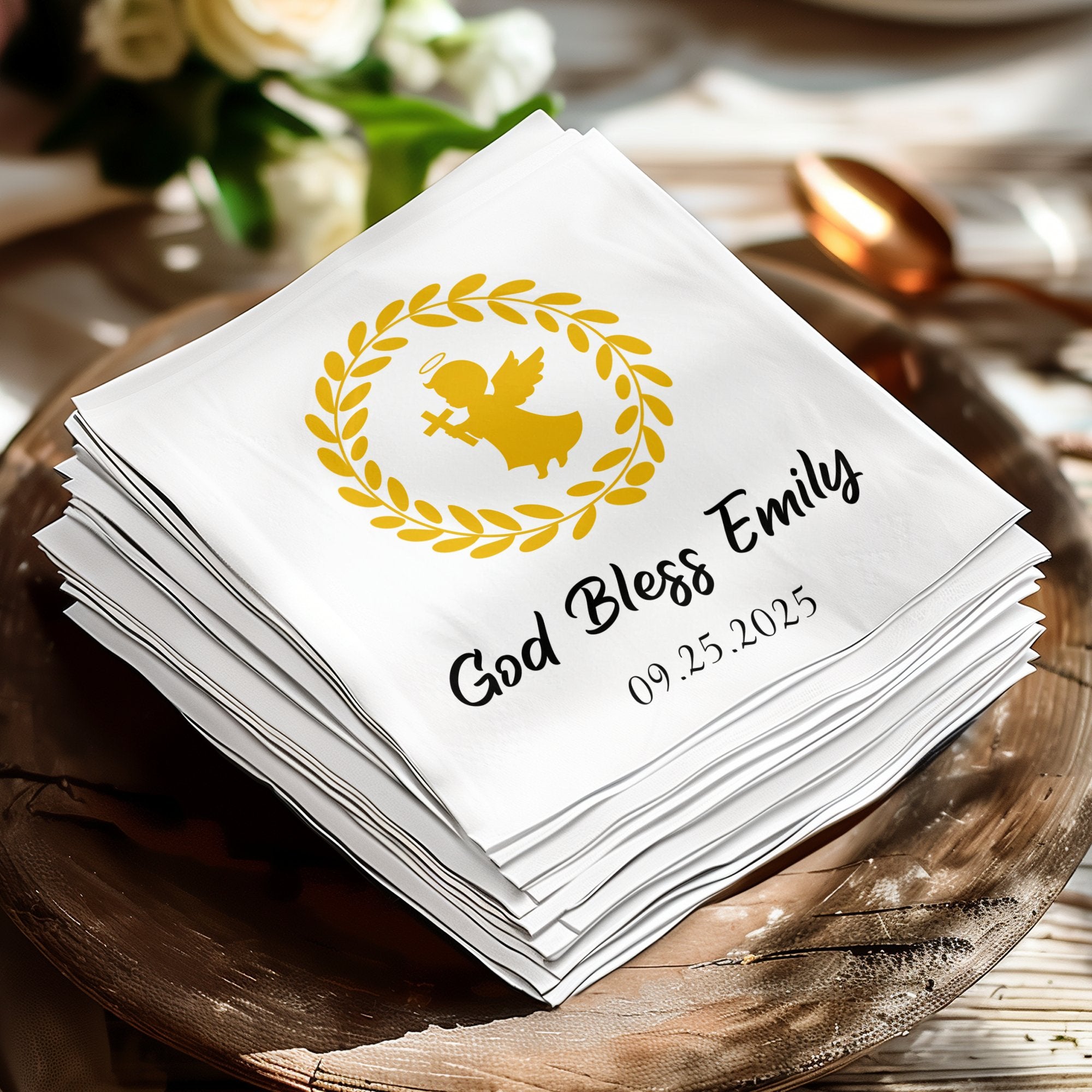 White napkin with golden angel, wreath, and text "God Bless Emily 09.25.2025".