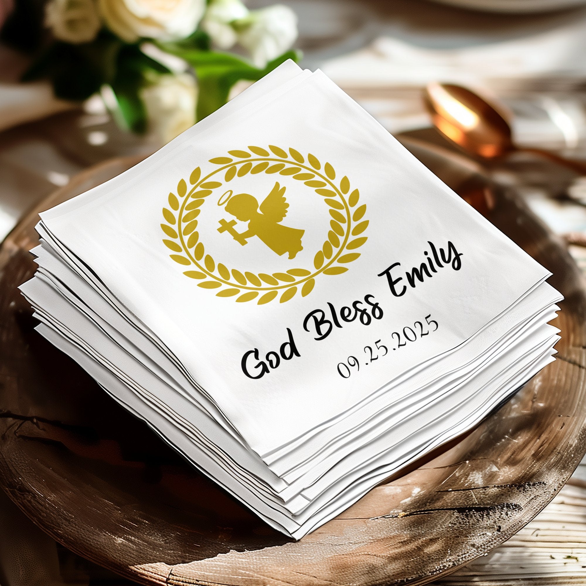 Stack of white napkins with gold angel, laurel wreath, and "God Bless Emily" text.