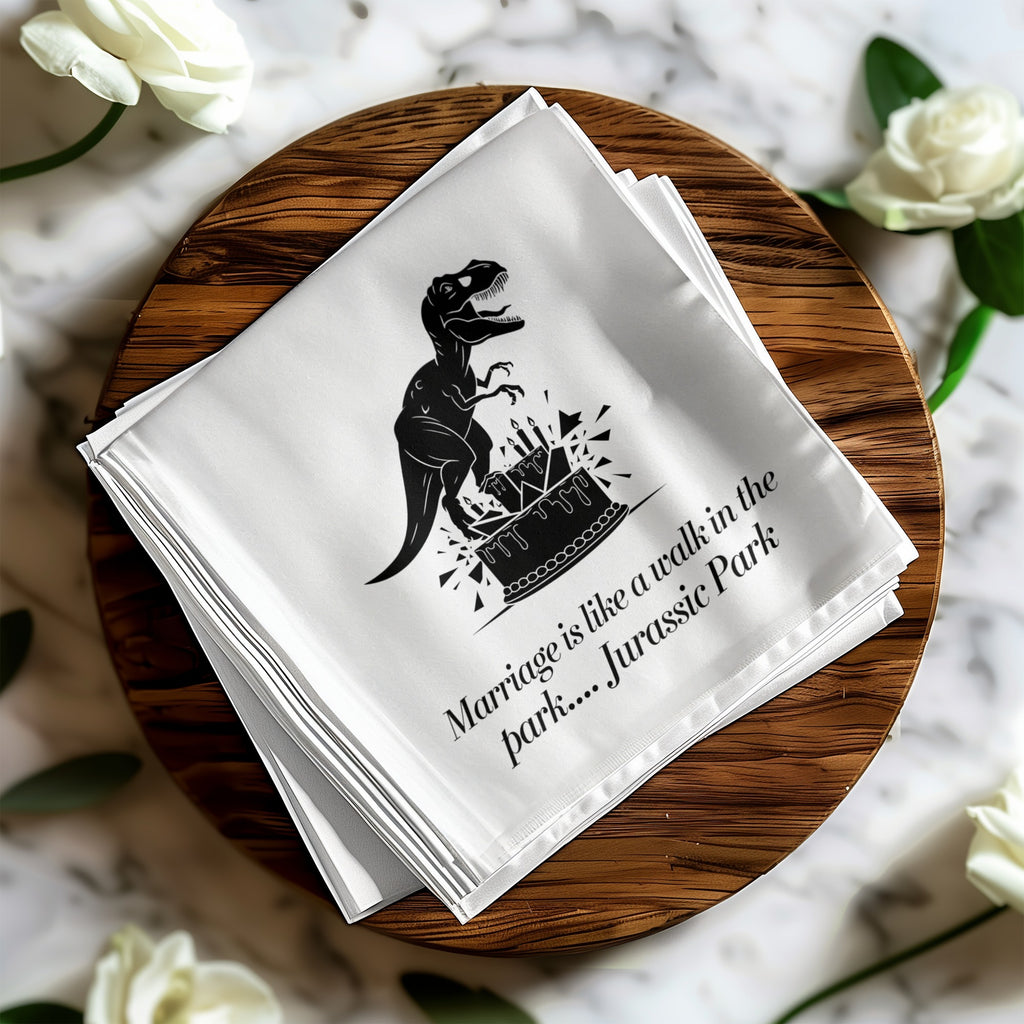 White napkin with dinosaur and wedding cake illustration and text "Marriage is like a walk in the park.... Jurassic Park".