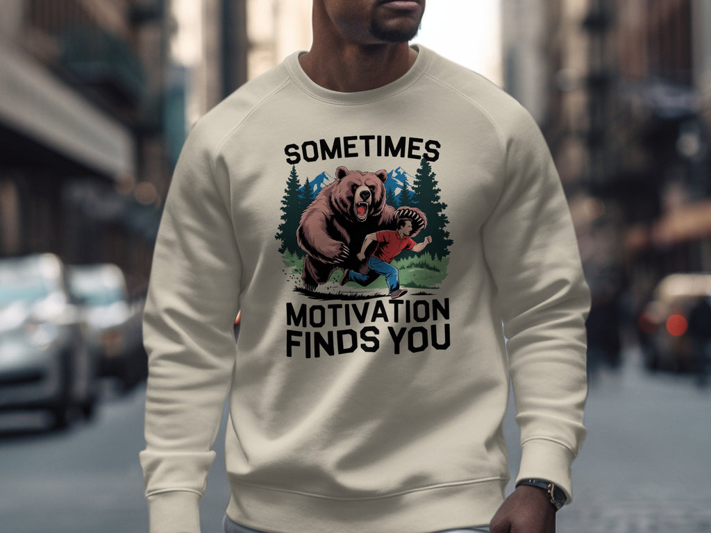 Crewneck sweatshirt with graphic of man running from bear and text "Sometimes Motivation Finds You".