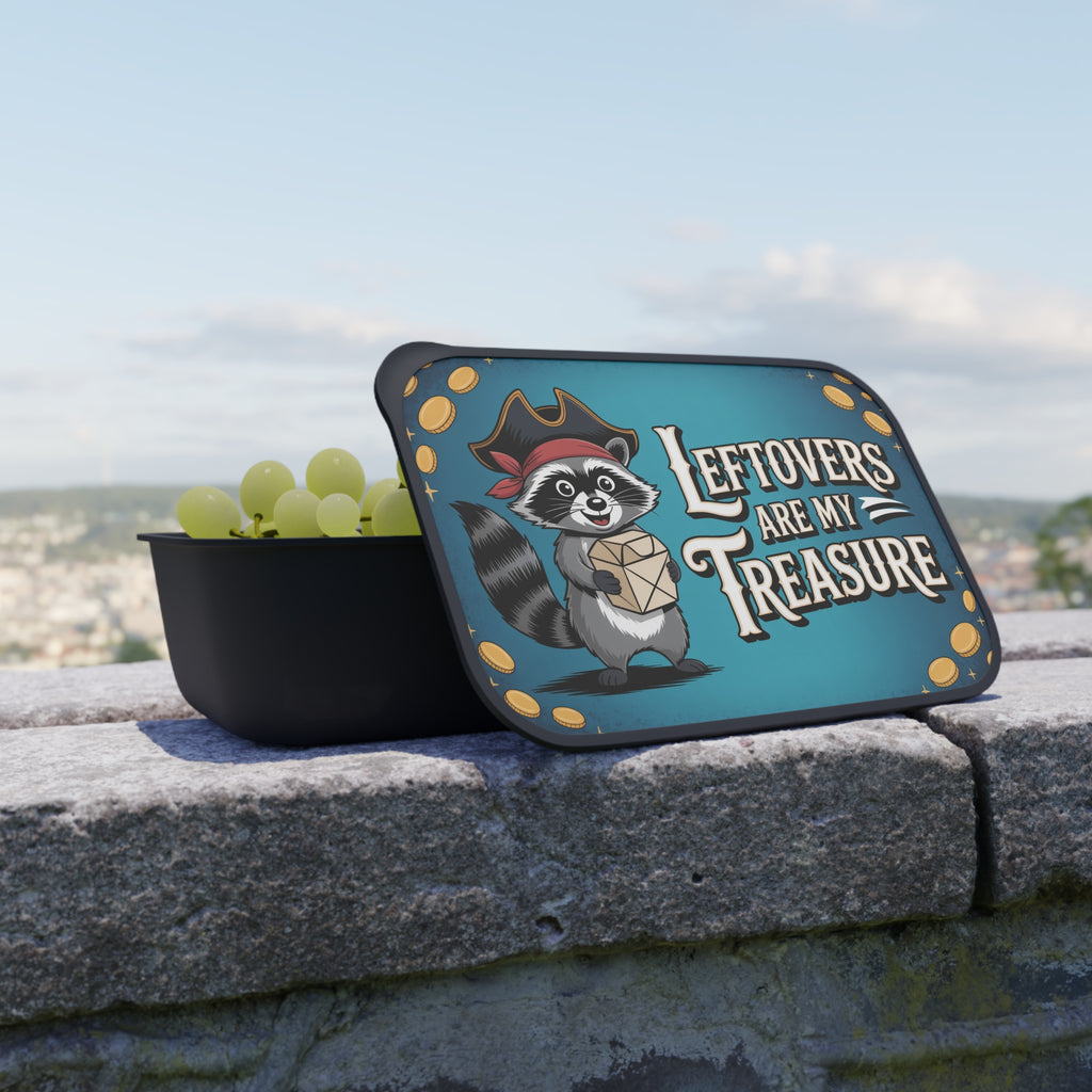 Raccoon in pirate hat holding a treasure chest over a bowl of grapes.