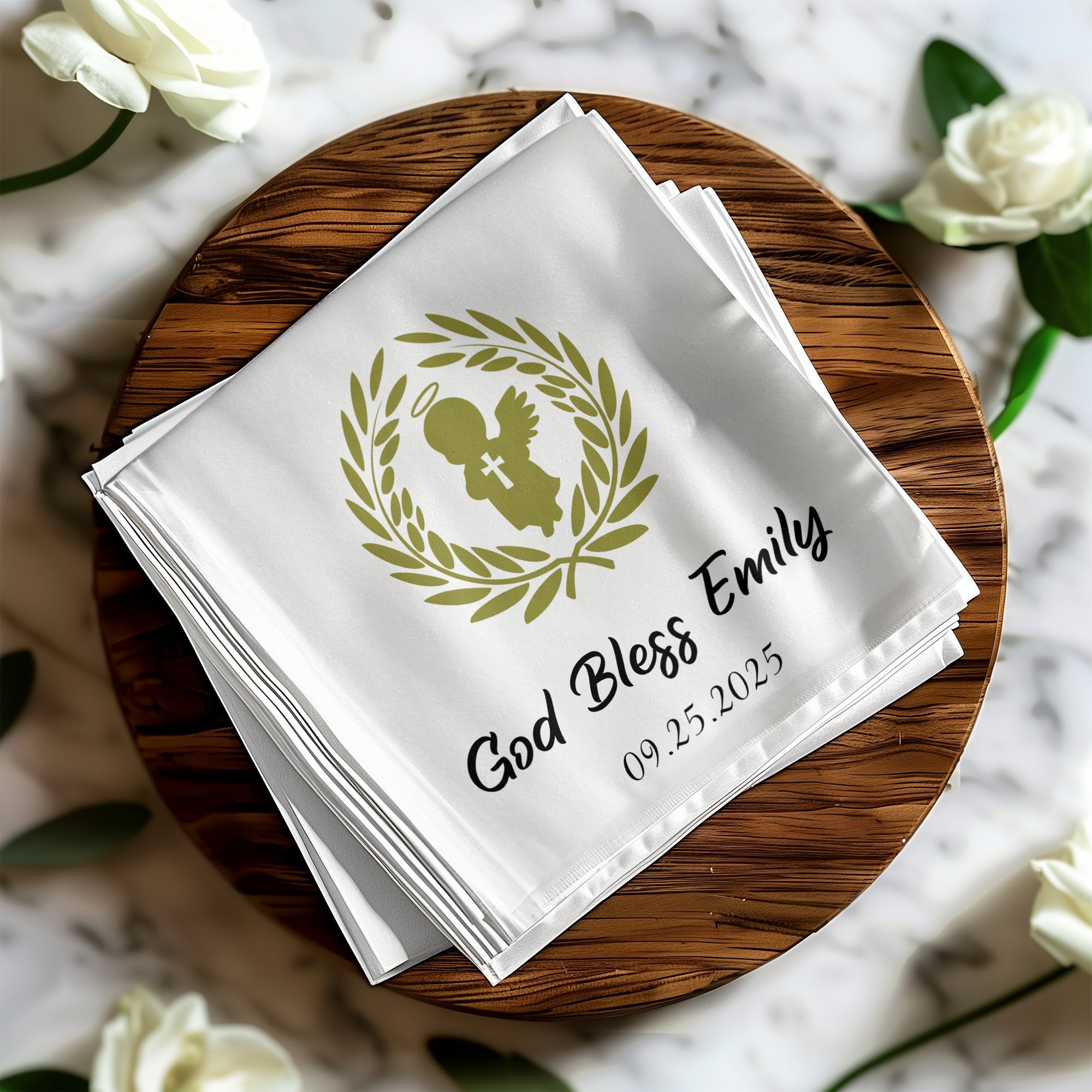 White cloth napkin with "God Bless Emily 09.25.2025" and laurel wreath.