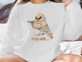 Cartoon bird with a gun on a branch, text "Stay still...".