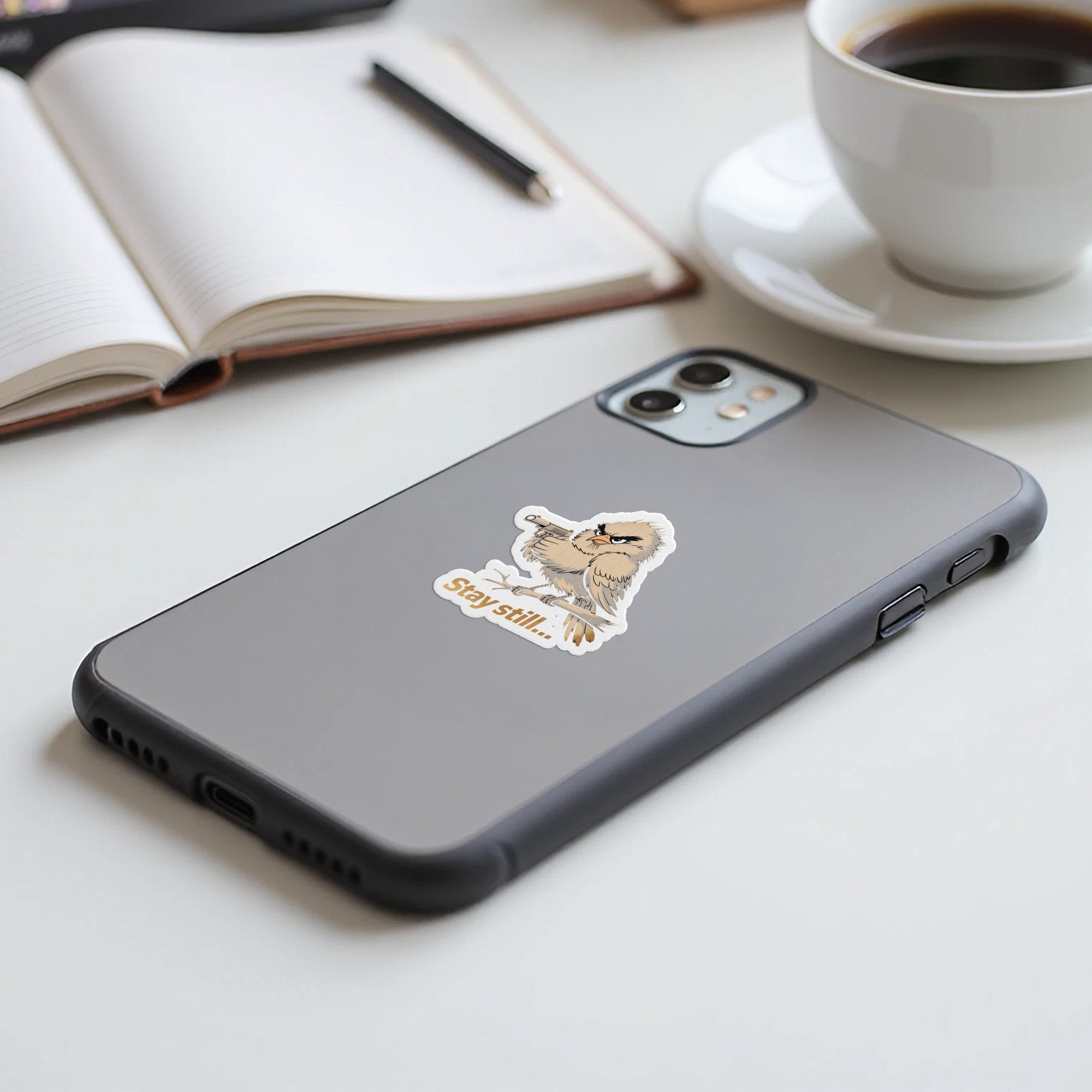 Sticker of an owl with "Stay still..." text on a smartphone.