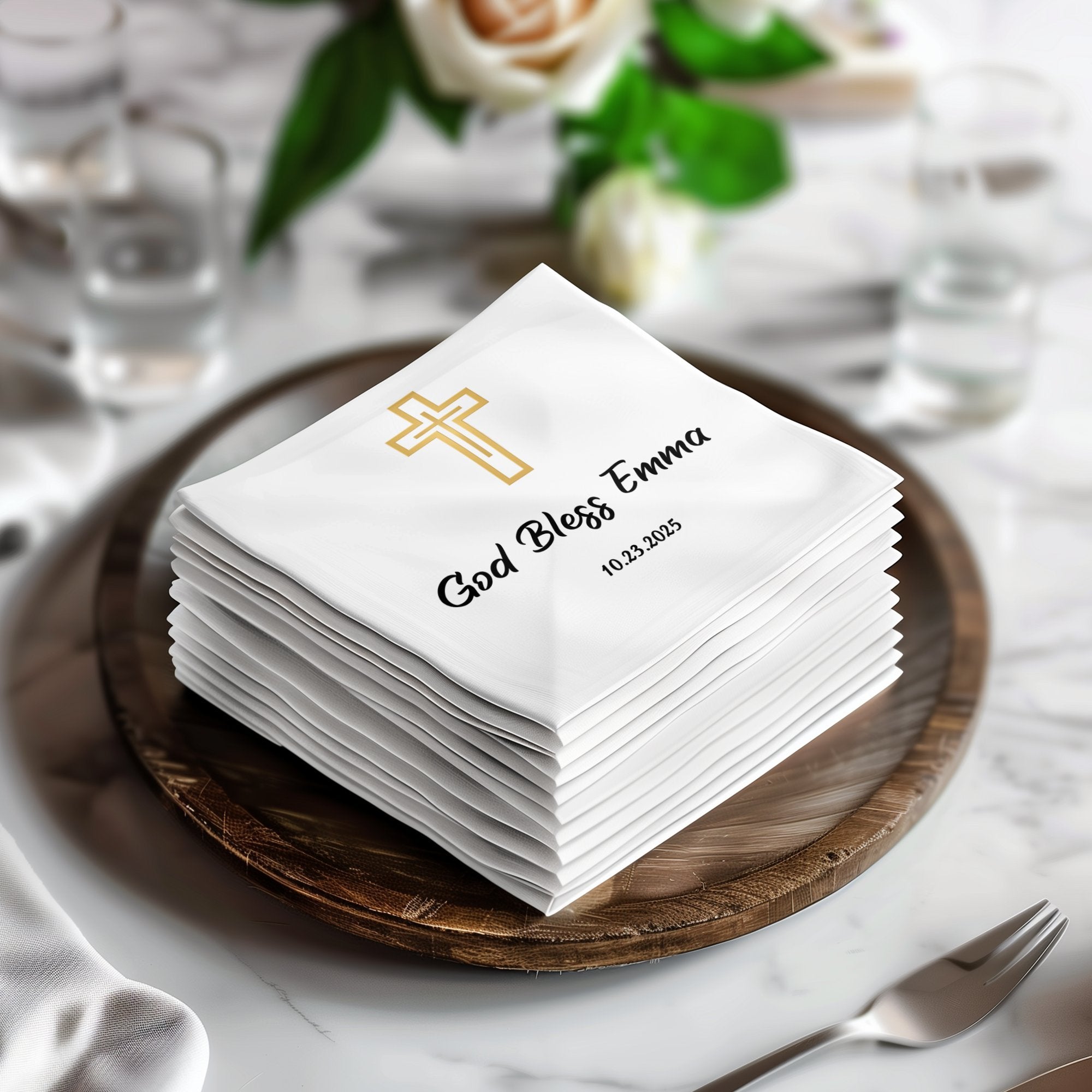 Stack of white napkins with gold cross and "God Bless Emma" text.