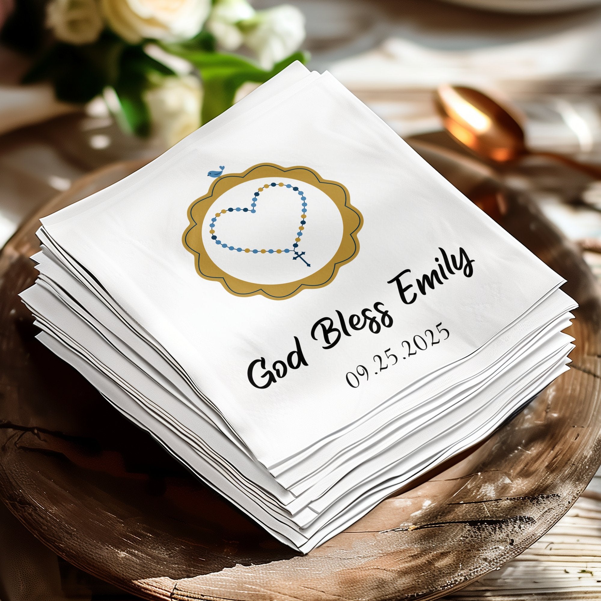 White napkins stacked with "God Bless Emily" and a heart rosary design.