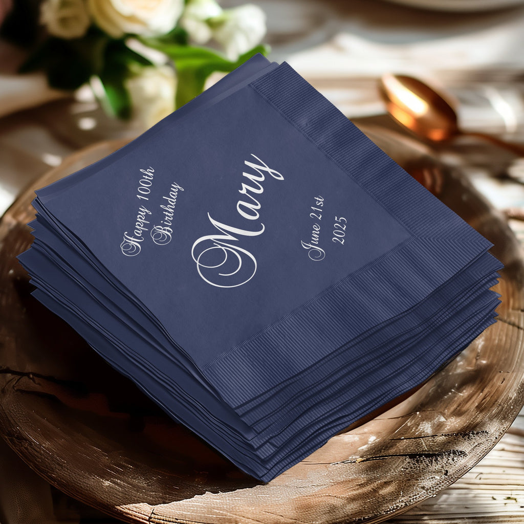 Stack of navy blue napkins with "Happy 100th Birthday Mary" and "June 21st, 2025" printed in white.