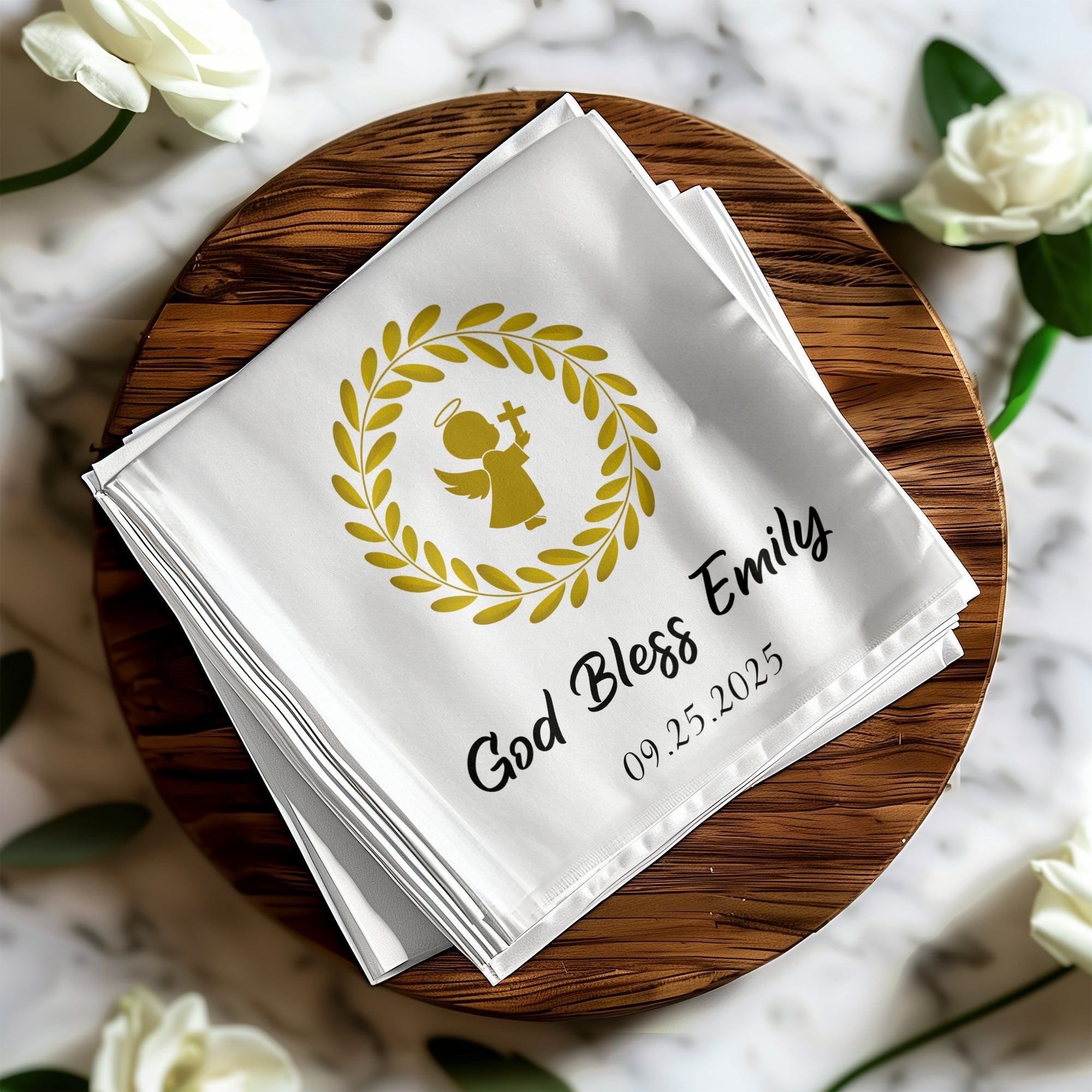 White napkin with gold angel, wreath, "God Bless Emily," and date.