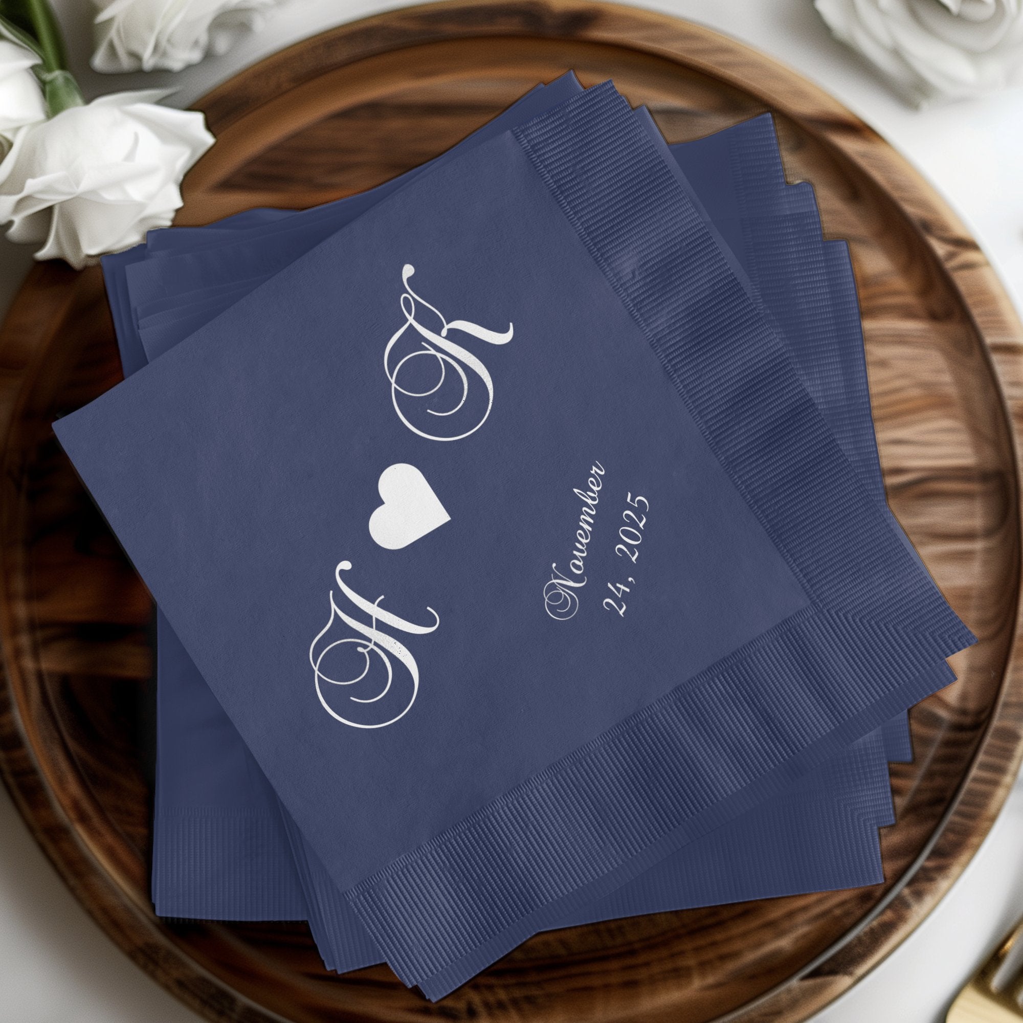 Navy cocktail napkins with white script initials "H & K" and "November 24, 2025".