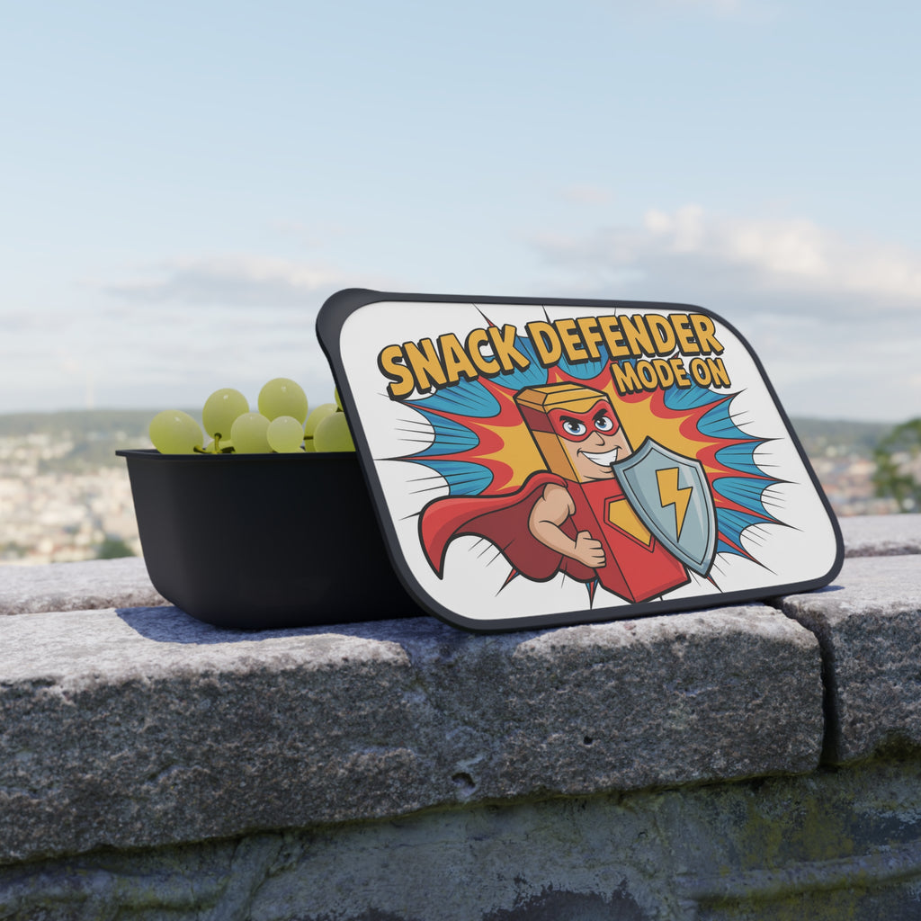 Black snack container with "Snack Defender" logo and green grapes.