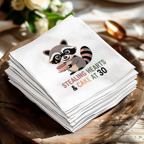 Stack of cocktail napkins featuring a raccoon holding a birthday cake with text.
