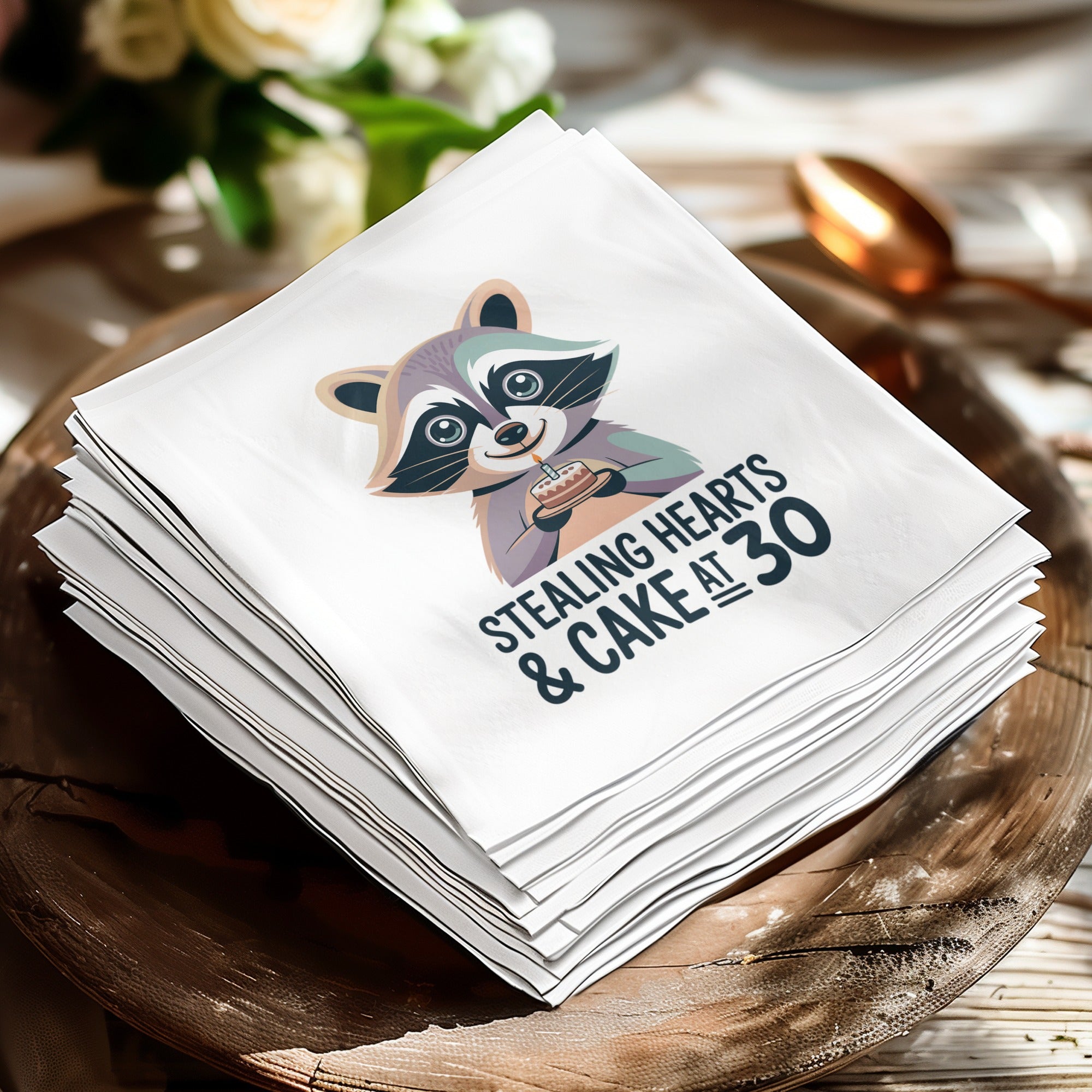 Napkin with raccoon holding cake, text "Stealing Hearts & Cake at 30".