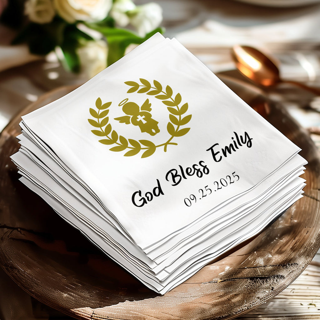 White cocktail napkin with gold angel and "God Bless Emily 09.25.2025".