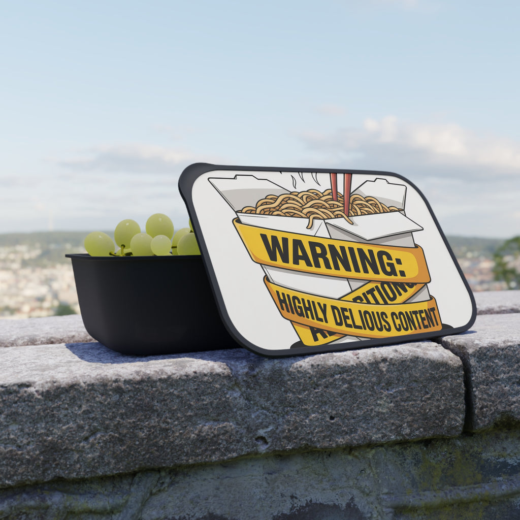 Black container with noodles, chopsticks, and "WARNING: HIGHLY DELICIOUS CONTENT" label.