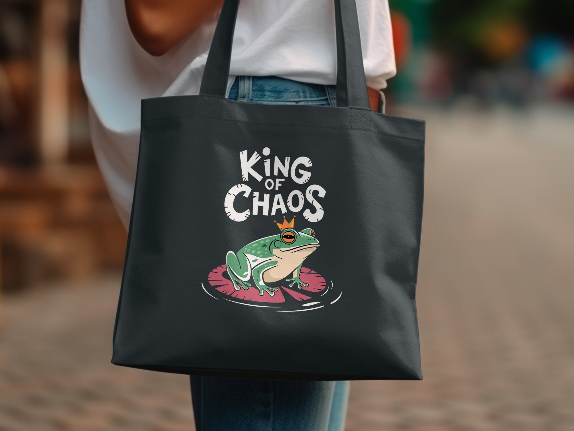 Dark tote bag with a cartoon frog wearing a crown on a lily pad.