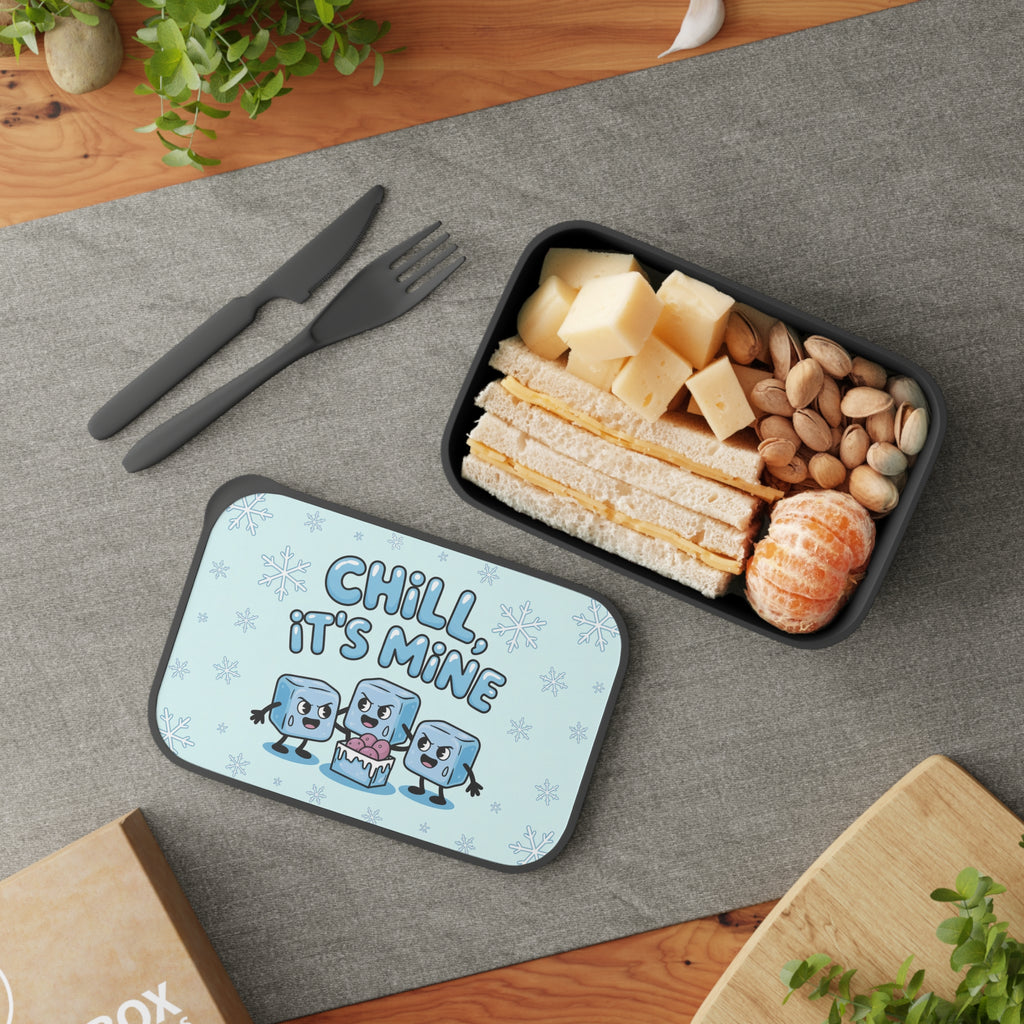 Lunchbox with "Chill, It's Mine" text and cartoon ice cubes next to a sandwich and fruit.